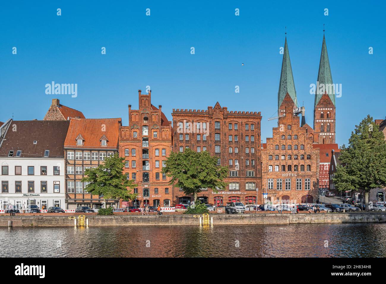 Lübeck, Fischer- und Tourismusboote vertäuten an der Trave.die beiden gotischen Glockentürme der Bordsteinkirche Santa Maria. Lübeck, Deutschland Stockfoto