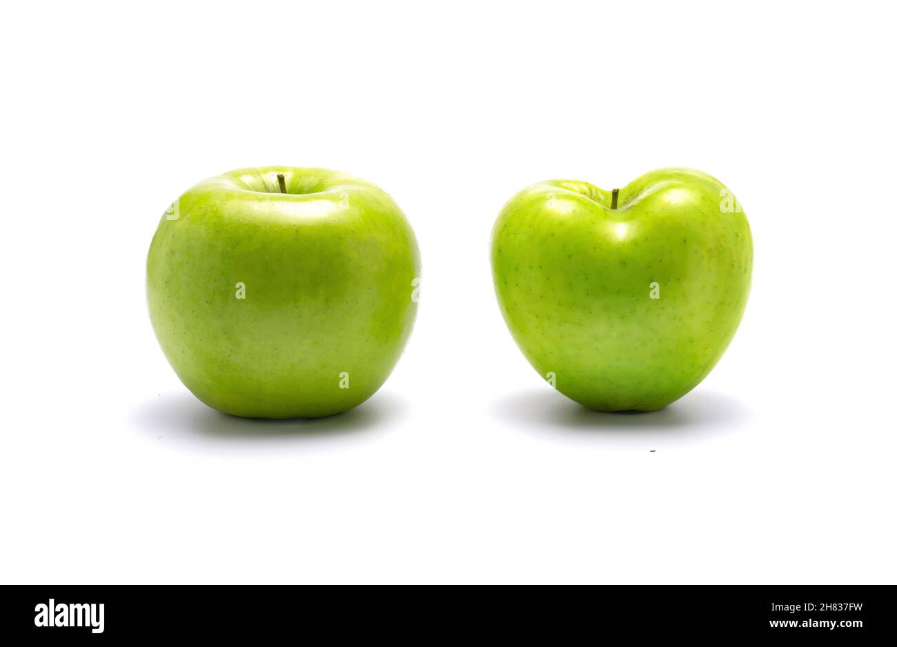 Zwei grüne Äpfel, ein Herz geformt. Auf weißem Hintergrund mit abgefallenem Schatten. Stockfoto