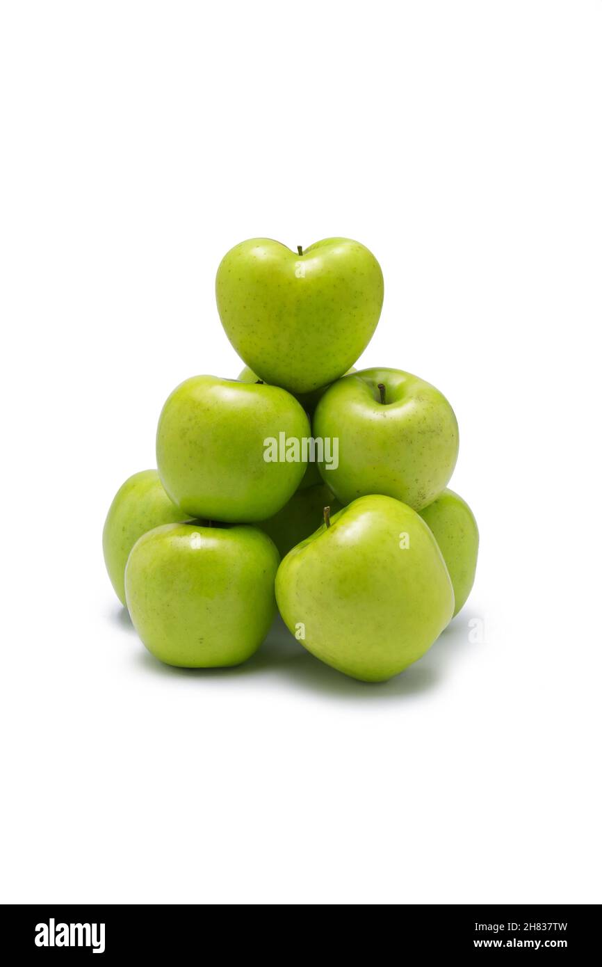 Grüne Äpfel, gestapelt in einer Gruppe mit einem Herz auf der Oberseite. Auf weißem Hintergrund. Stockfoto