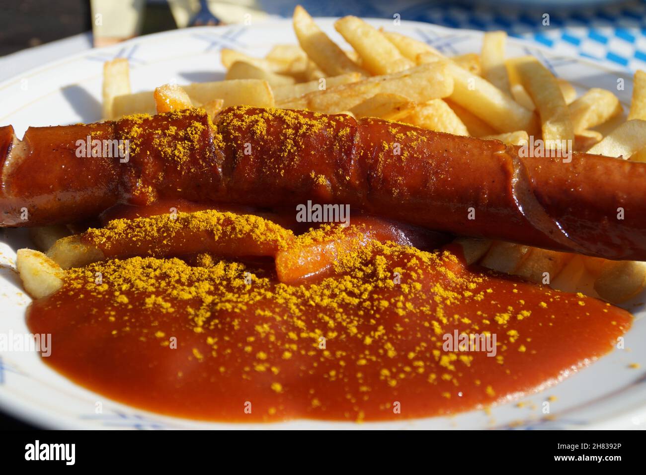 Köstliche heiße frittierte deutsche Currywurst mit knusprigen pommes Frites und Currysauce Stockfoto
