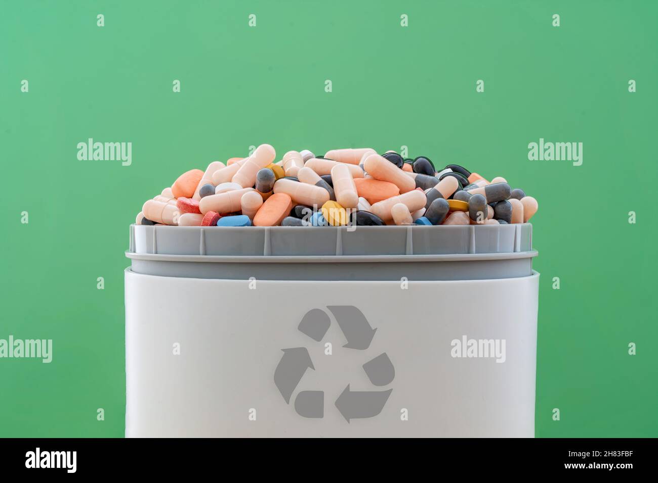 Voll mit abgelaufenen Pillen und Medikamenten im Abfalleimer mit Recycling-Symbol. Abfalltabletten gesammelt, um recycelt zu werden. Abfallmanagement-Konzept. Stockfoto