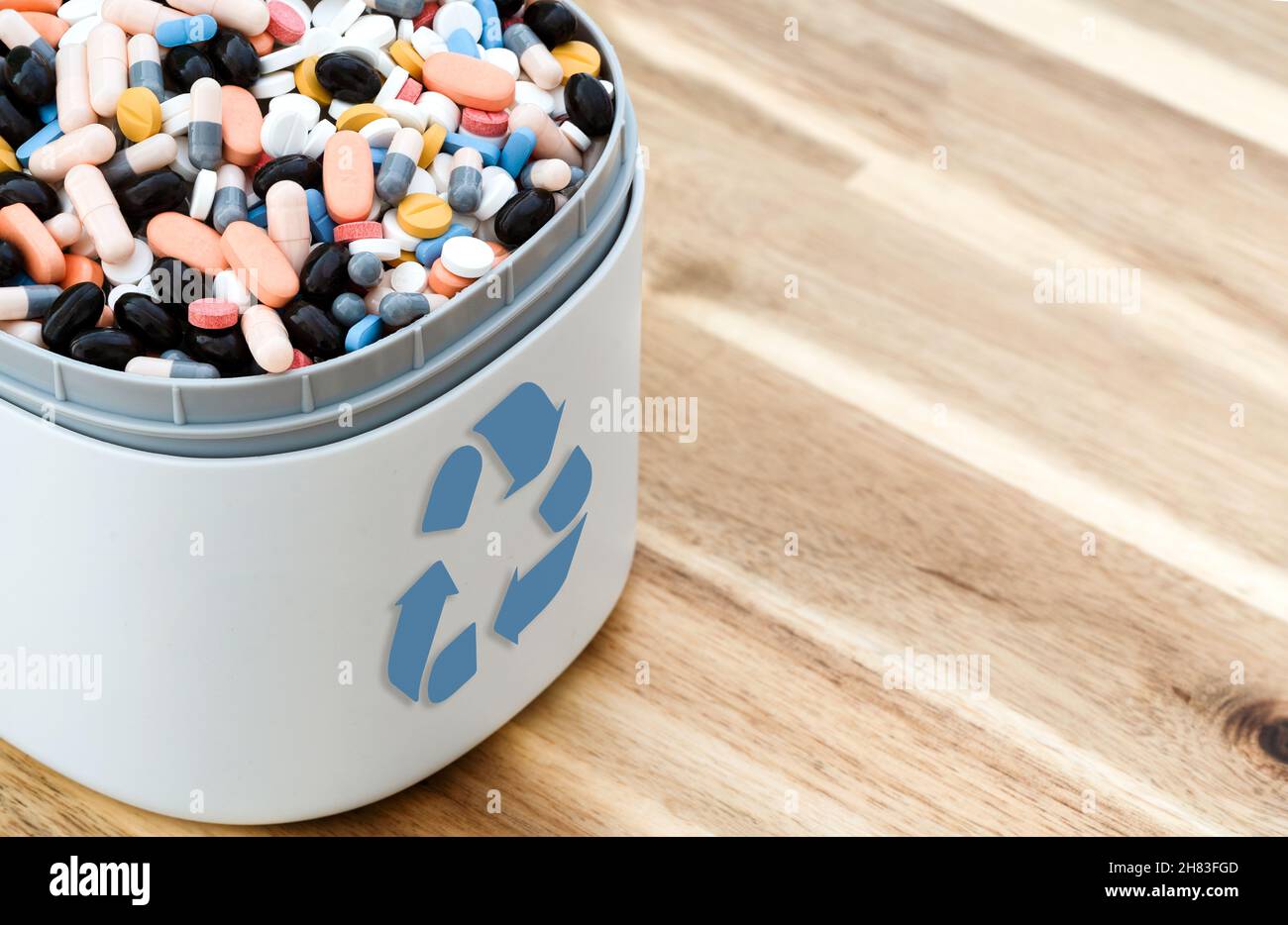 Voll mit abgelaufenen Pillen und Medikamenten im Abfalleimer mit Recycling-Symbol. Abfalltabletten gesammelt, um recycelt zu werden. Abfallmanagement-Konzept. Stockfoto