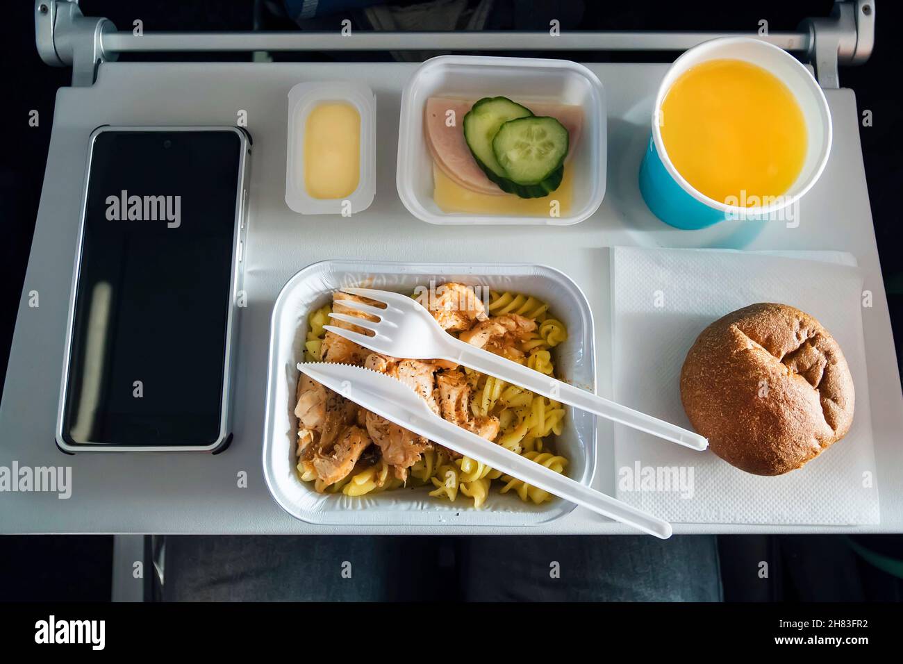 Vorbereitete Lebensmittel auf dem Flugzeug. Kunststoff Besteck Messer und Gabel in einem Teller mit Lebensmitteln. Bescheidene, preiswerte Passagiere der Economy-Klasse für Lebensmittel, die Low-Cost-ai reisen Stockfoto