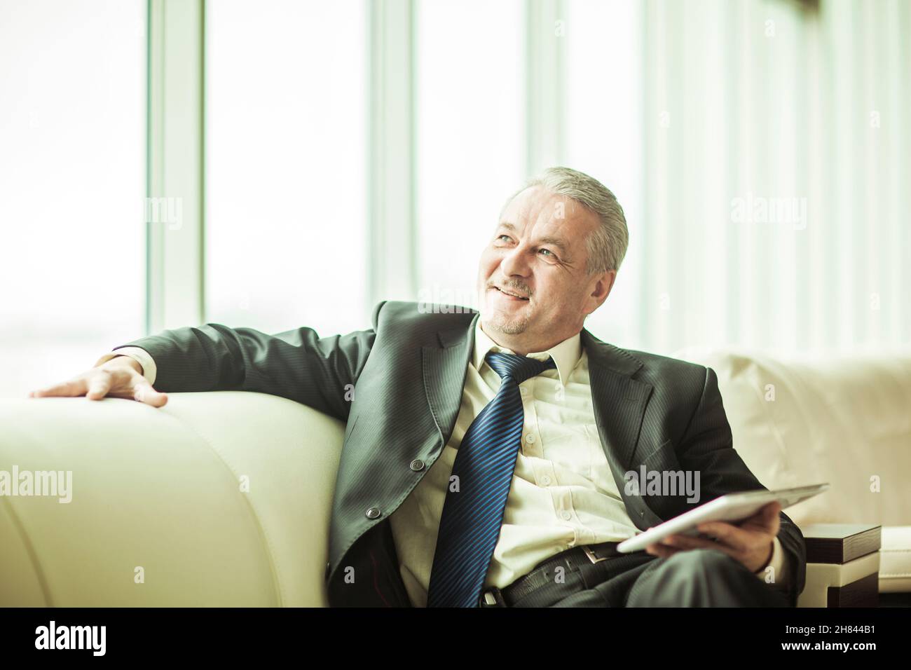 Erfahrenen Rechtsanwalt mit digitalen Tablet auf dem Sofa sitzen im eigenen Büro Stockfoto