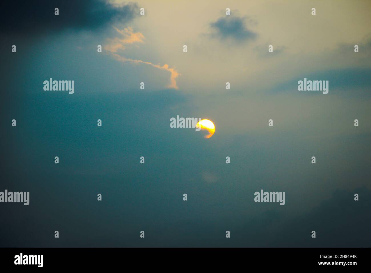 Sonnenuntergang an einem trüben Sommertag mit teilweise hinter Wolken verborgener Sonne - blaue Stunde am Abend Stockfoto