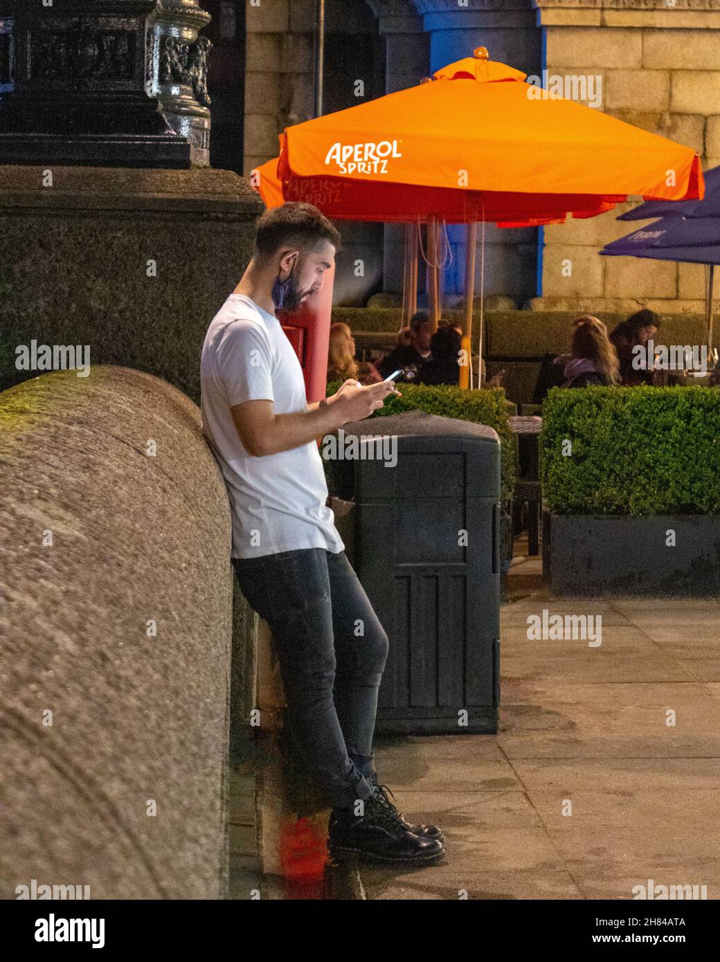 Ein Mann, der eine Zigarette raucht und sein Mobiltelefon auf der Southbank in London anschaut, während er eine Pause von der Arbeit nimmt. London. Stockfoto