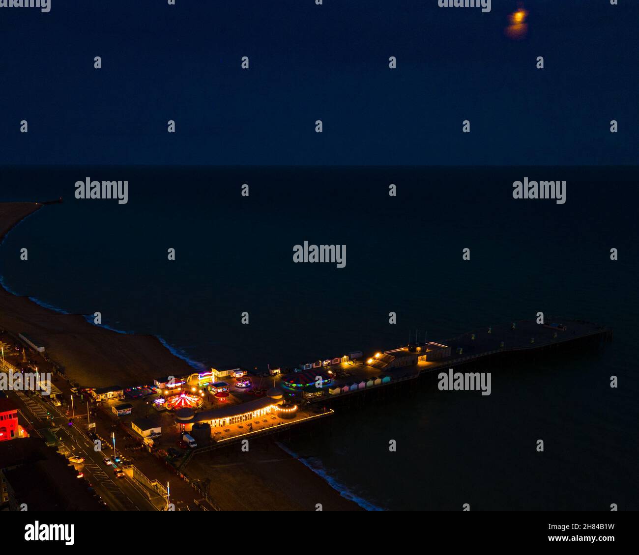 Eine Luftaufnahme von Hastings, Sussex, Großbritannien, England, aufgenommen zur blauen Stunde, wobei der Pier beleuchtet und ins Meer ragt. Stockfoto