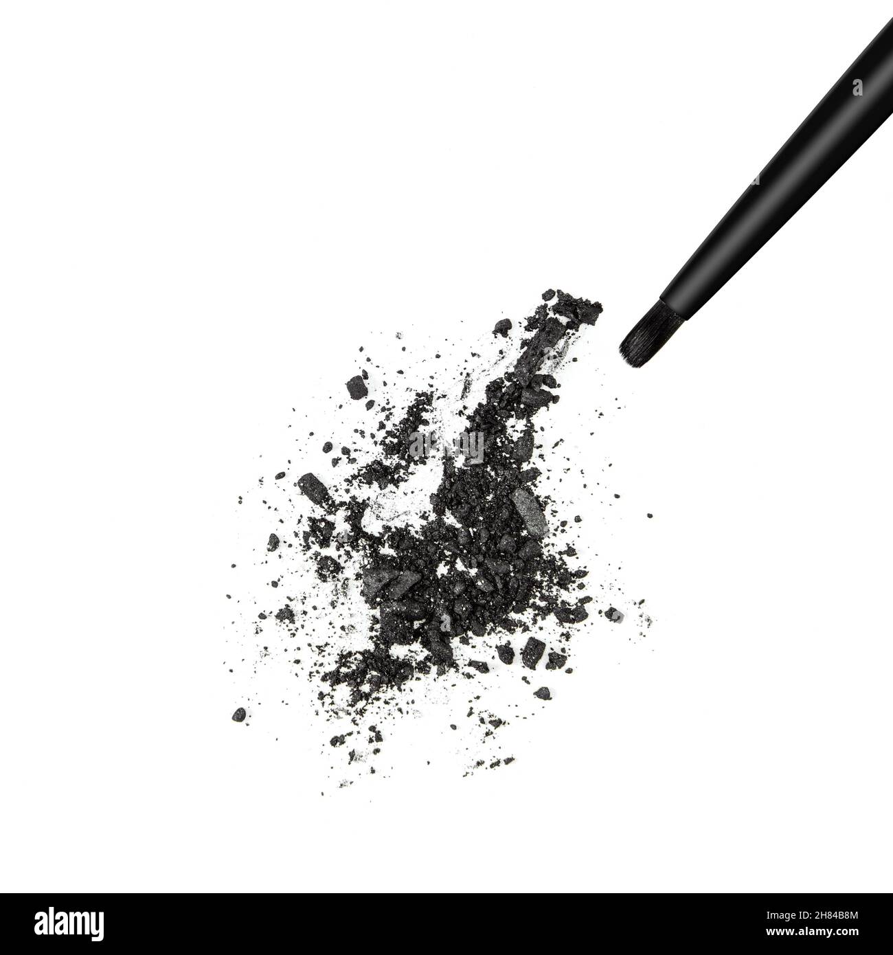 Nahaufnahme von zerkleinerten schwarzen schimmernden Lidschatten mit Make-up-Pinsel auf weißem Hintergrund Stockfoto