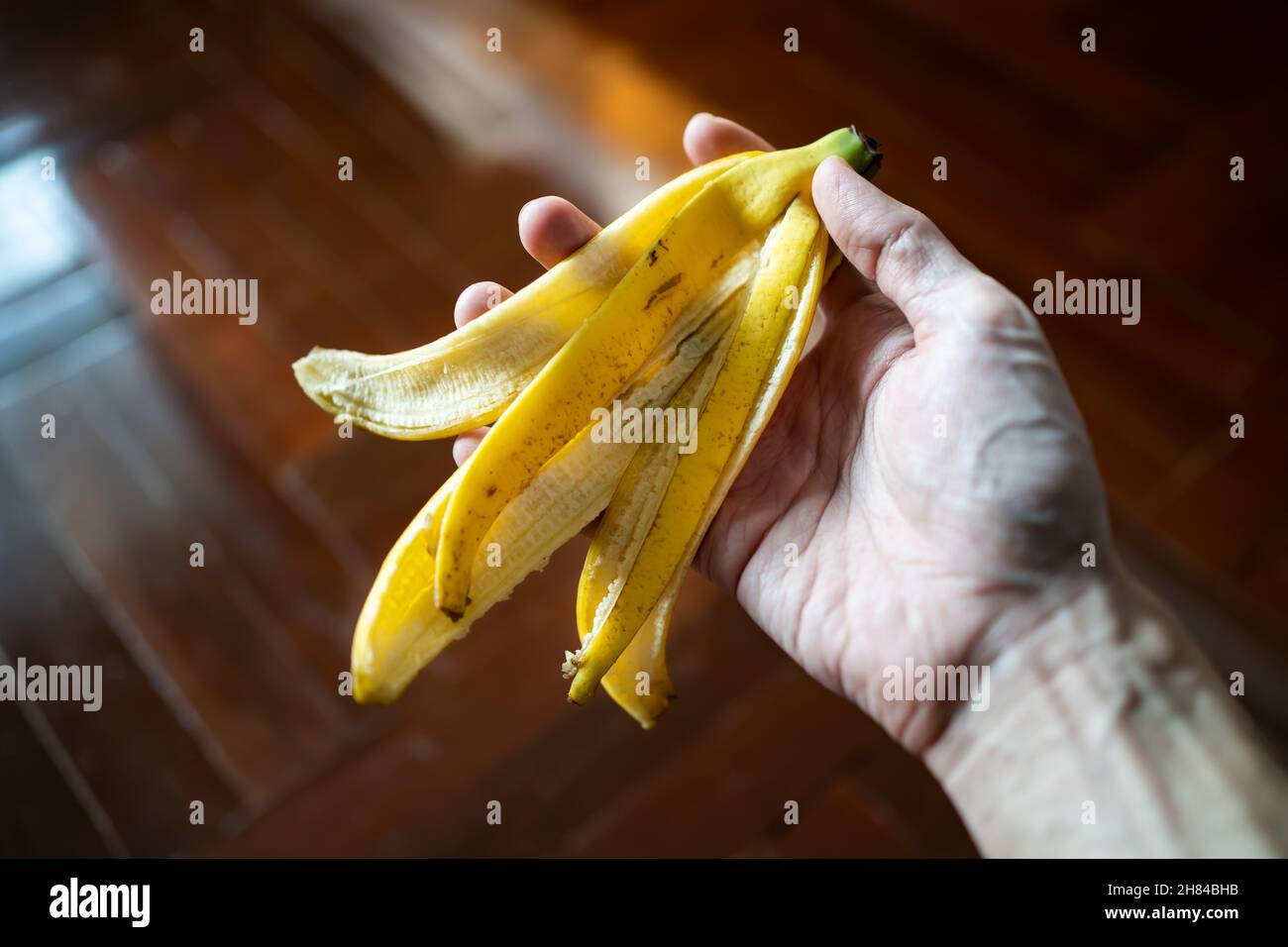 Bananenschale in Männerhand. Bananenschalen sind essbar und nahrhaft. Stockfoto