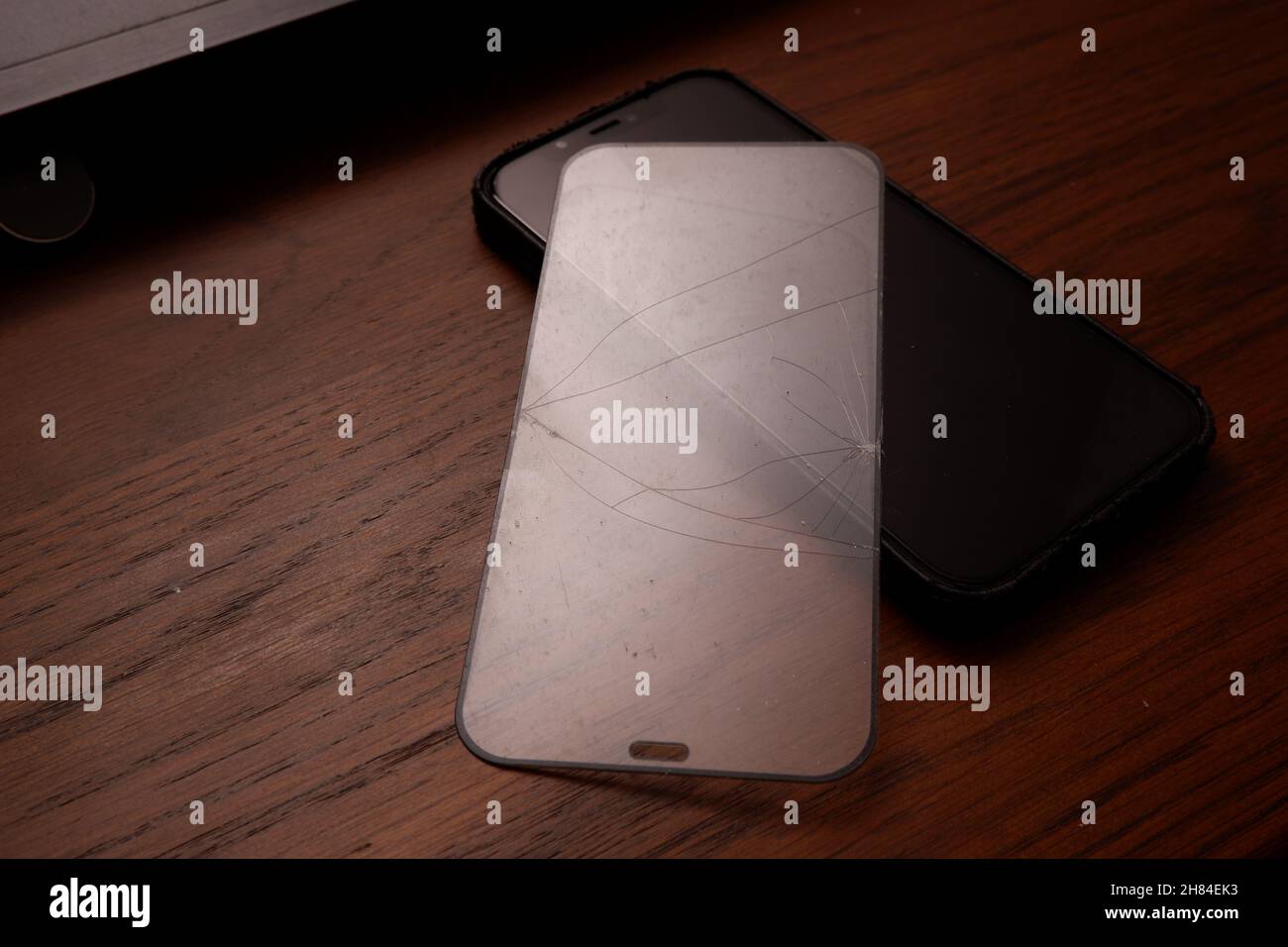 Zerbrochene Displayschutzfolie des Smartphones auf einem Holztisch Stockfoto