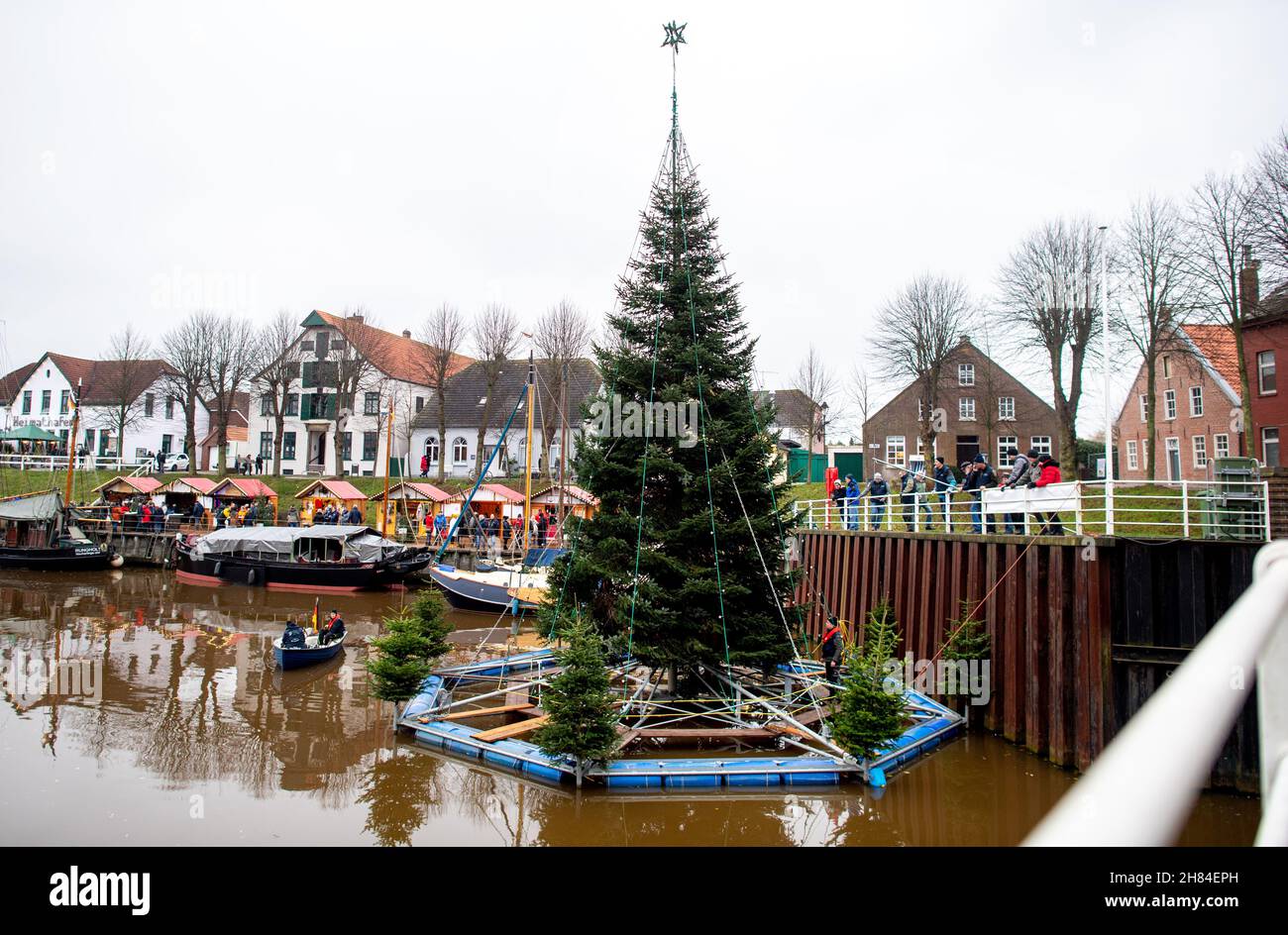 Carolinensiel, Deutschland. 27th. November 2021. Der schwimmende Weihnachtsbaum wird von Freiwilligen im Hafen des Dorfes aufgestellt. Seit 1995 wird der Baum traditionell am Samstag vor dem ersten Adventssonntag aufgesetzt und die Lichter eingeschaltet. Quelle: Hauke-Christian Dittrich/dpa/Alamy Live News Stockfoto