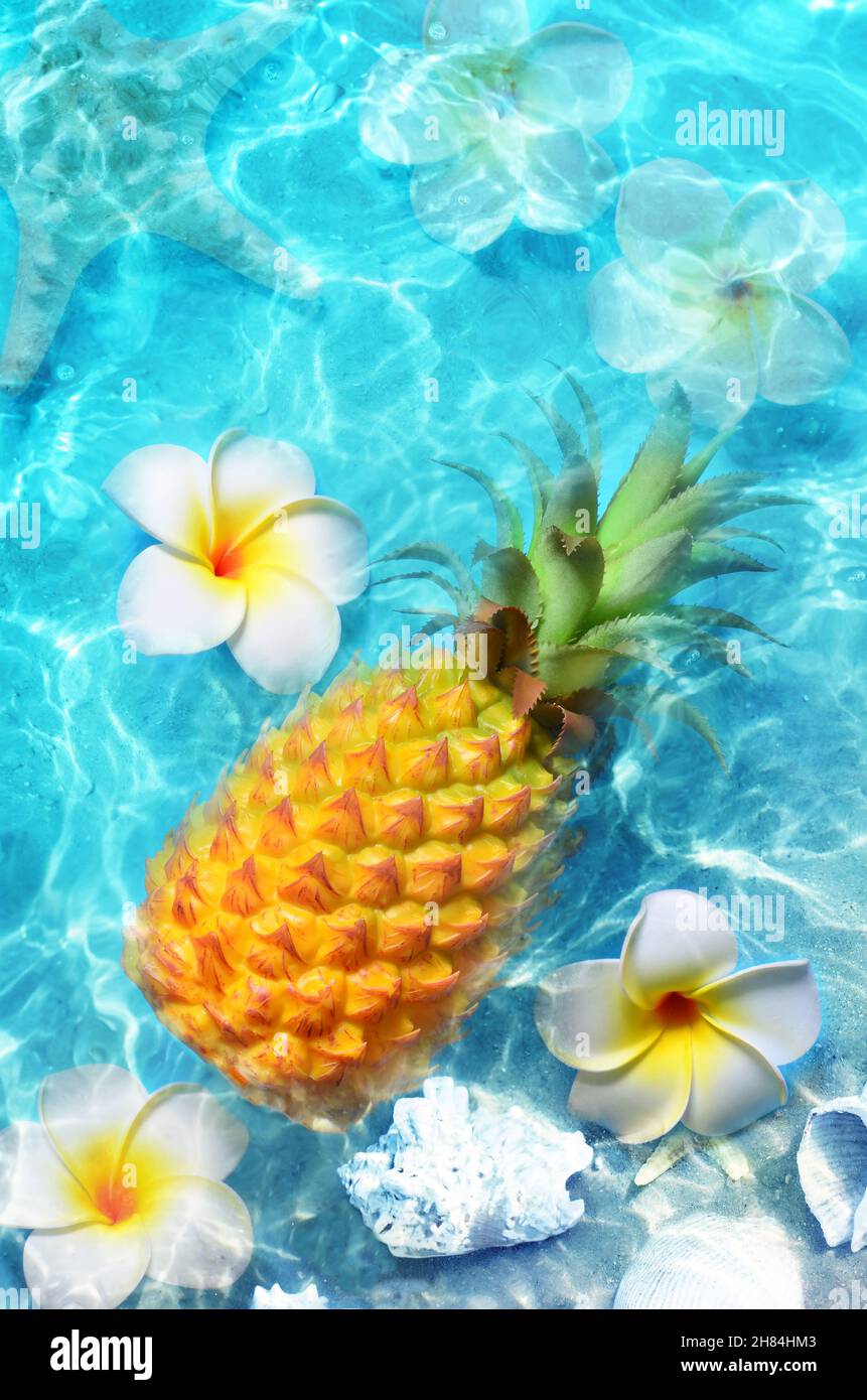 Gelbe Ananas und weiße Blüten auf blauem Wasserhintergrund. Exotisches Konzept. Stockfoto