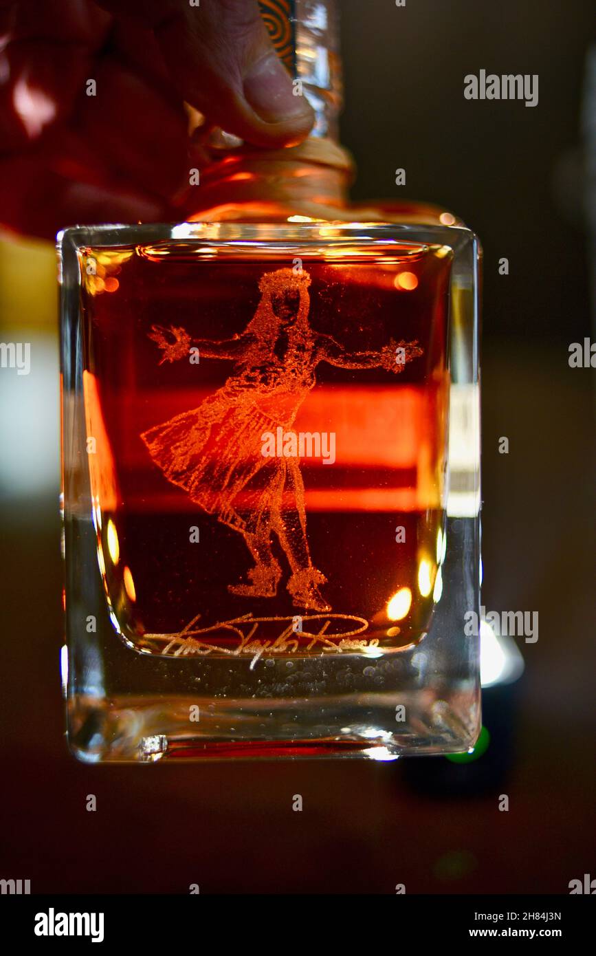 Hawaianisches Mädchen tanzt Hula, geätzt auf die Glasflasche gefüllt mit bernsteinfarbenem Kō Hana Hawaiian Agricole Rum, Kō Hana Distillers, Kunia, Hawaii, USA Stockfoto