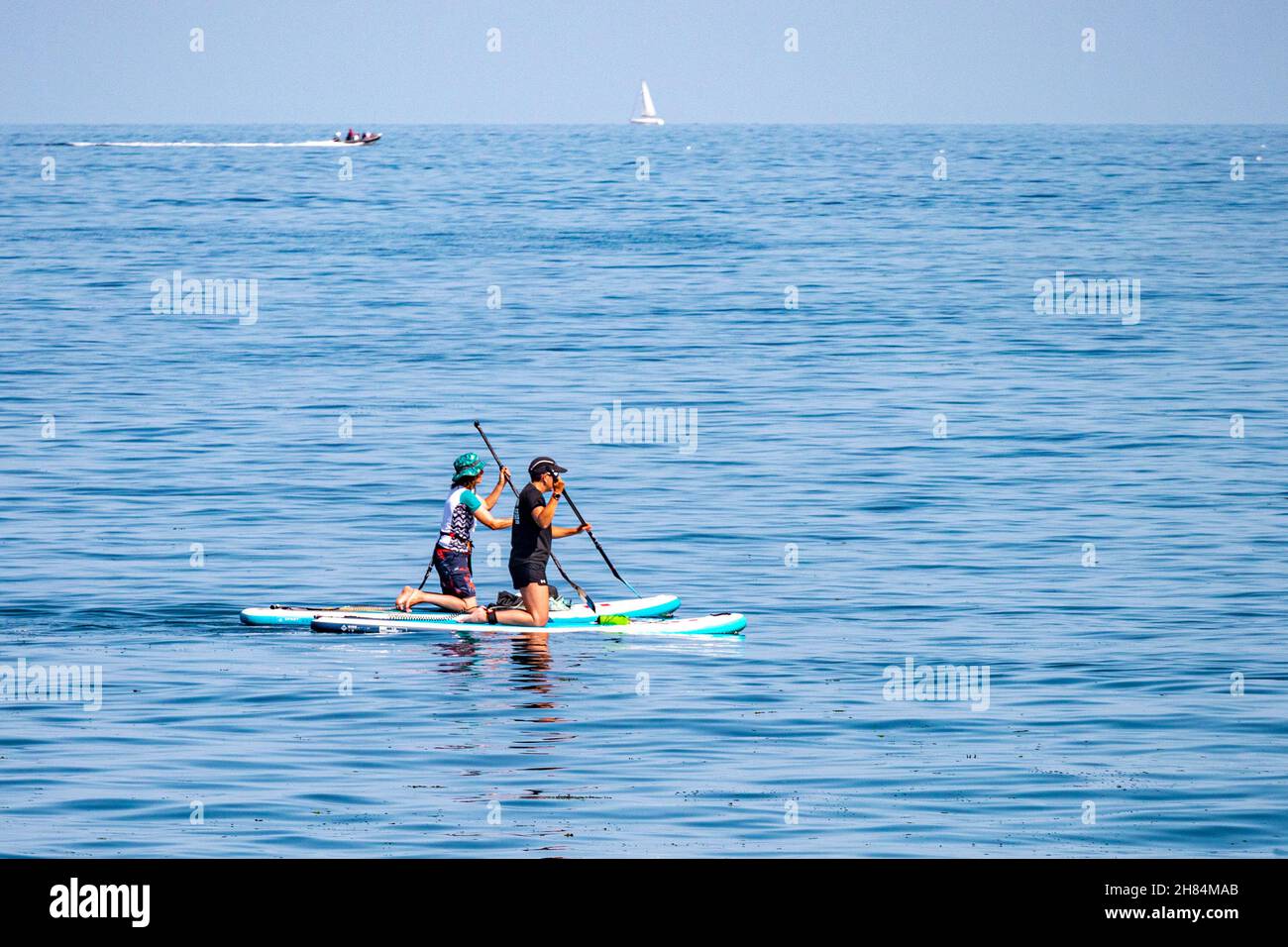 Paddelboarder auf einem ruhigen Meer vor Megavissey, Cornwall, Großbritannien. Stockfoto