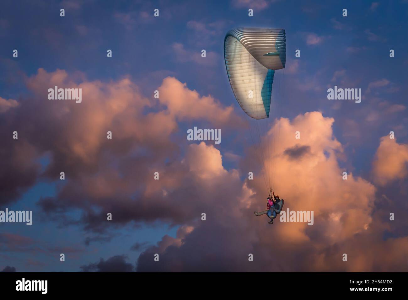 Tandem-Paragliding bei Sonnenuntergang an einem bewölkten Abend Stockfoto