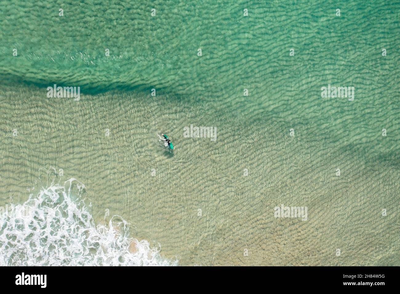 Luftaufnahme eines Surfers im klaren Wasser des tropisch anmutenden Pedn Vounder Beach, West Cornwall bei Ebbe im Winter. Stockfoto