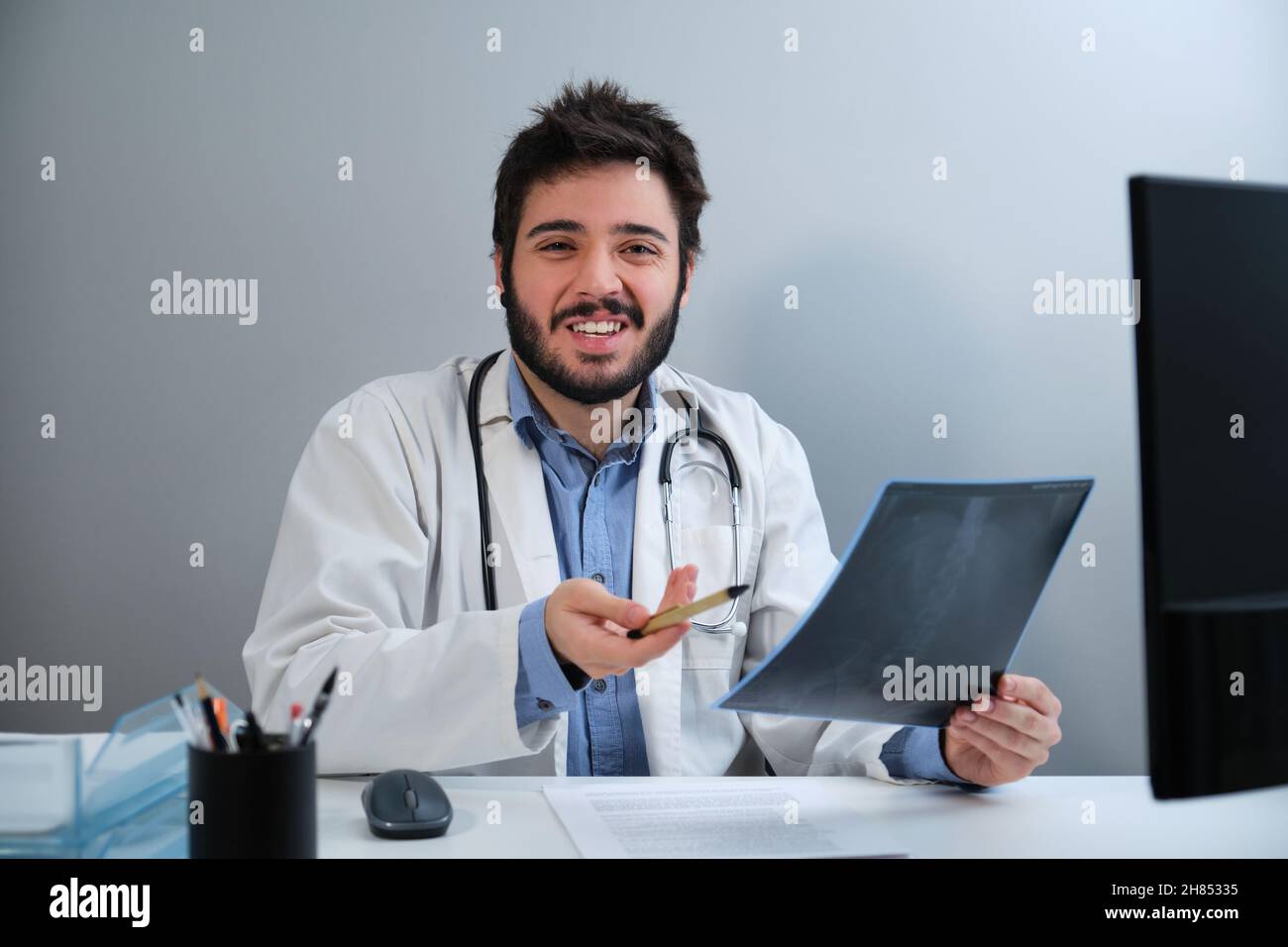 Der junge Arzt versteht die Röntgenaufnahme eines Beckens und einer Wirbelsäule am Schreibtisch nicht. Stockfoto