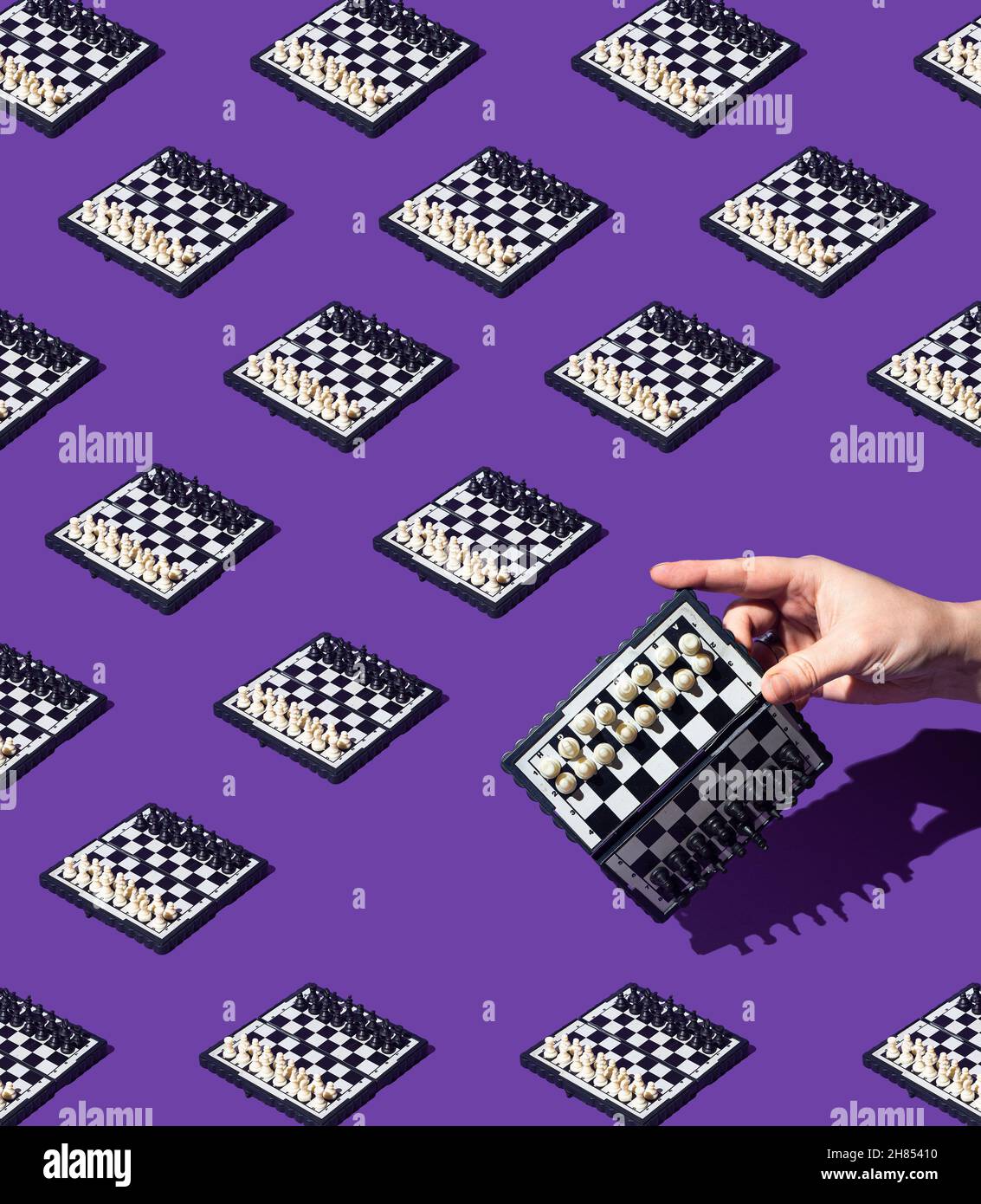 Nahtloses Schachbrettmuster auf einem monochrom-violetten Hintergrund. Die weibliche Hand hält das Schachbrett nach rechts geneigt. Schwarz-weißes Schachbrett. T Stockfoto