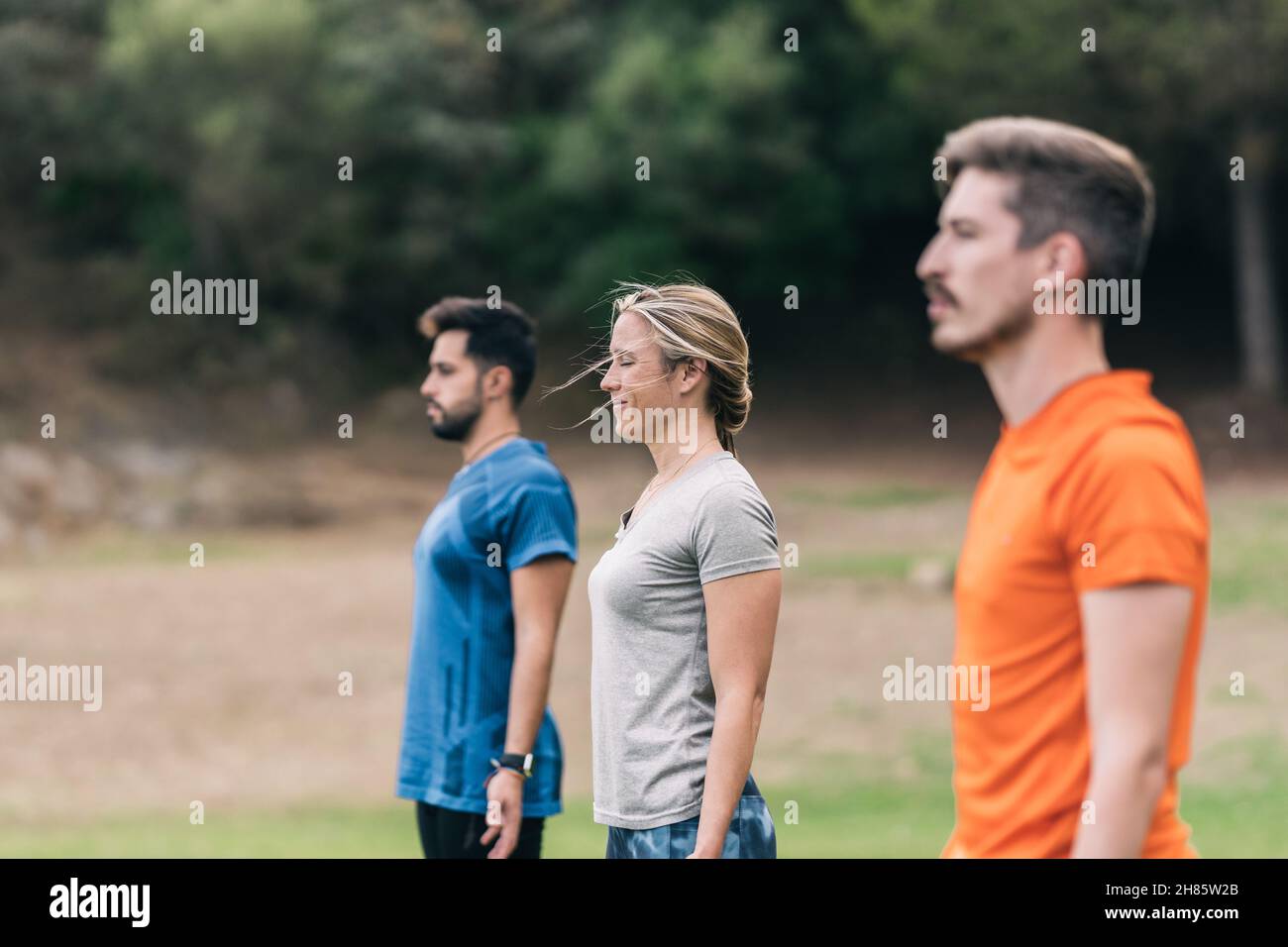 Drei Personen stehen und machen eine Yoga-Sitzung im Freien Stockfoto