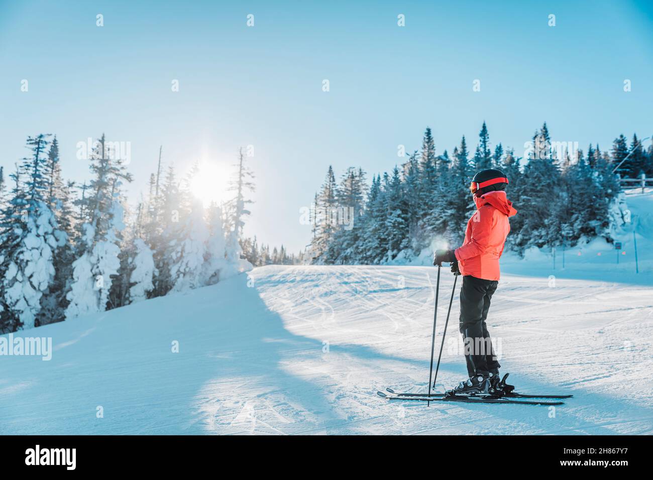 Alpine Abfahrt. Skimorträt einer alpinen Skifahrerin mit Skiern, Helm, cooler Skibrille und Hardshell-Winterjacke und Skihandschuhen bei Kälte Stockfoto