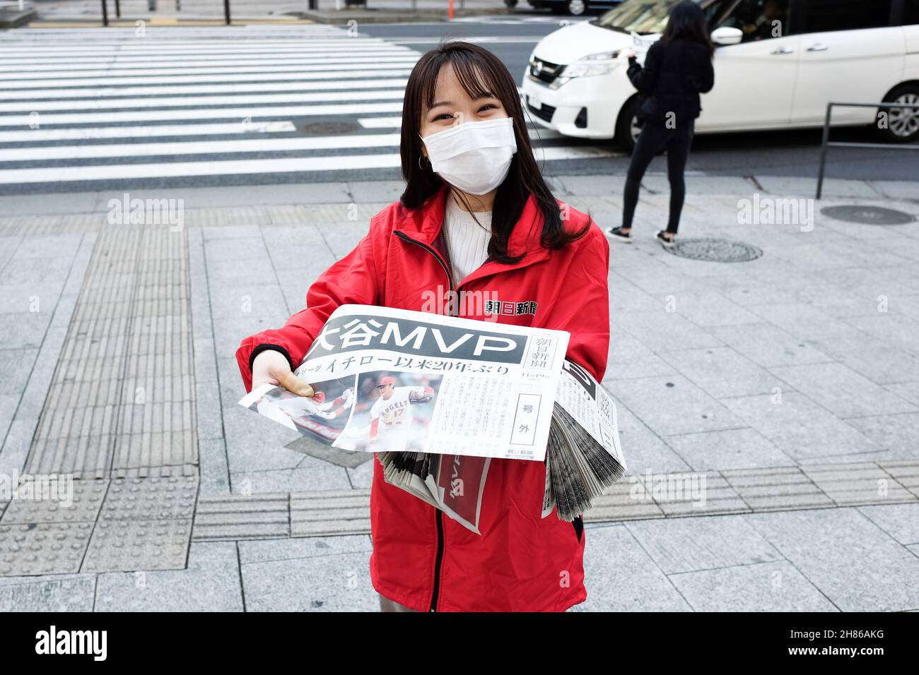 Eine Frau aus Tokio, Japan, verschenkt eine Souvenir-Zeitung, die die Ankündigung von Shohei Ohtani als MVP des amerikanischen Baseballs im November 2021 feiert. Stockfoto