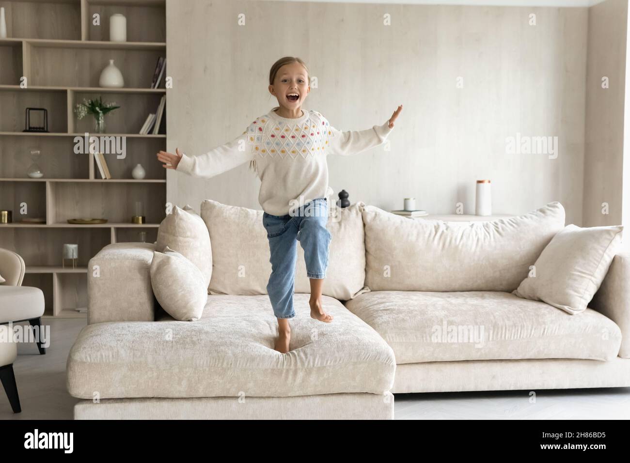 Portrait von fröhlichen sorglosen kleinen Mädchen springen auf dem Sofa. Stockfoto