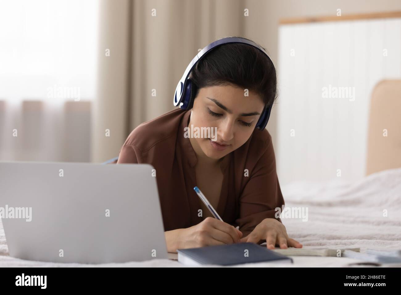 Konzentrierte junge indische Ethnie Frau hört pädagogische Vortrag am Computer. Stockfoto