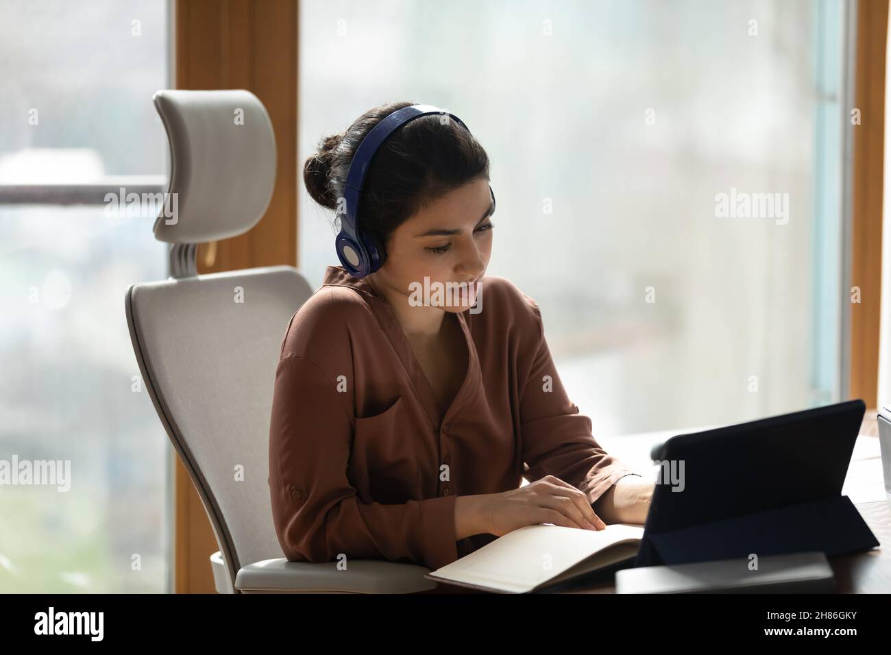 Konzentrierte junge inderin in Kopfhörer hören Vortrag auf Touchpad Stockfoto