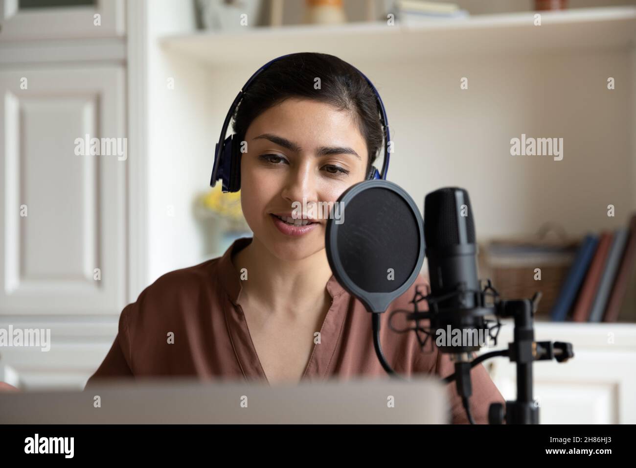 Schöne junge indische Frau, die Lied oder Stimme aufzeichnet. Stockfoto