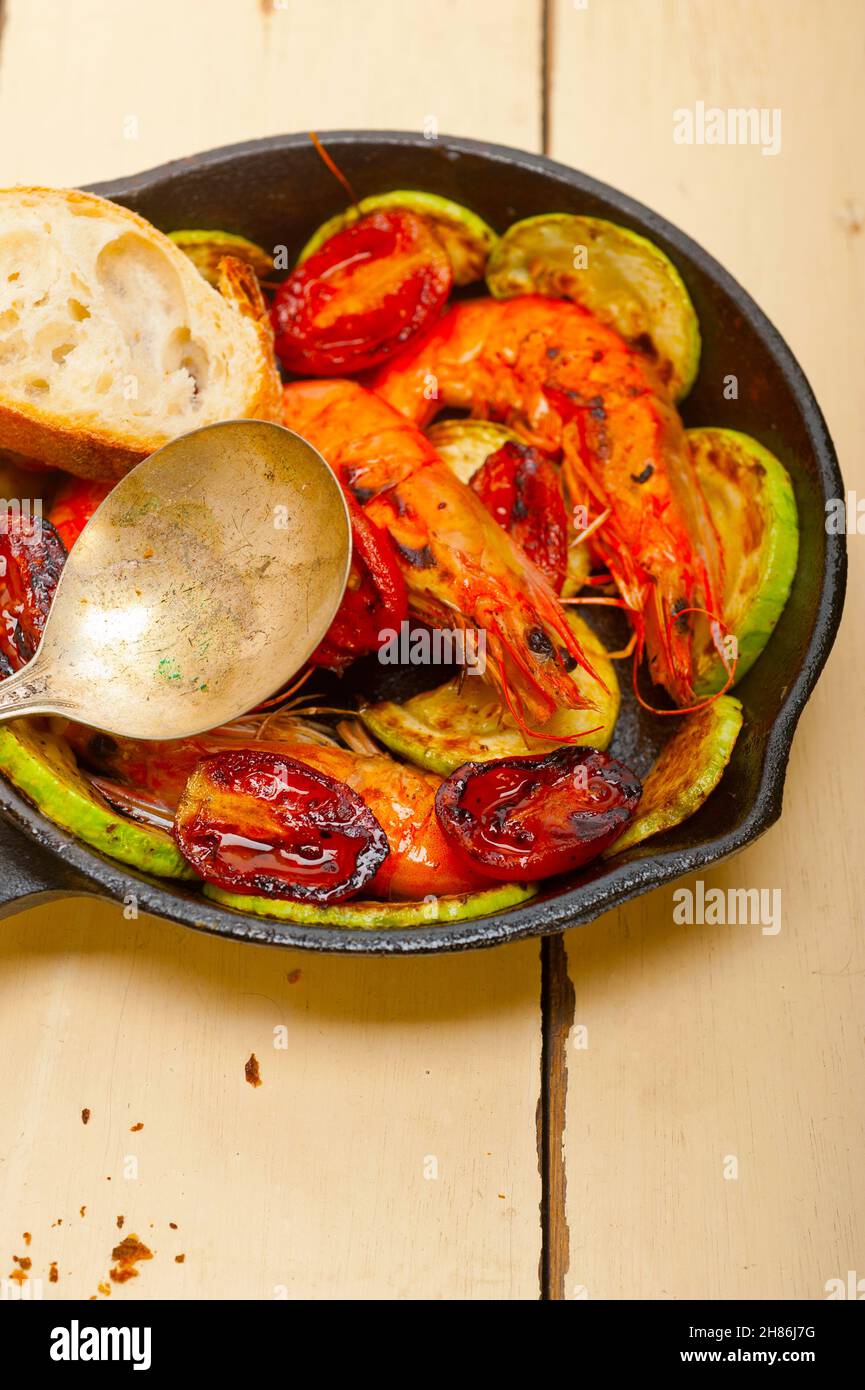 Gebratene Garnelen auf gusseisernen Pfanne mit Zucchini und Tomaten Stockfoto