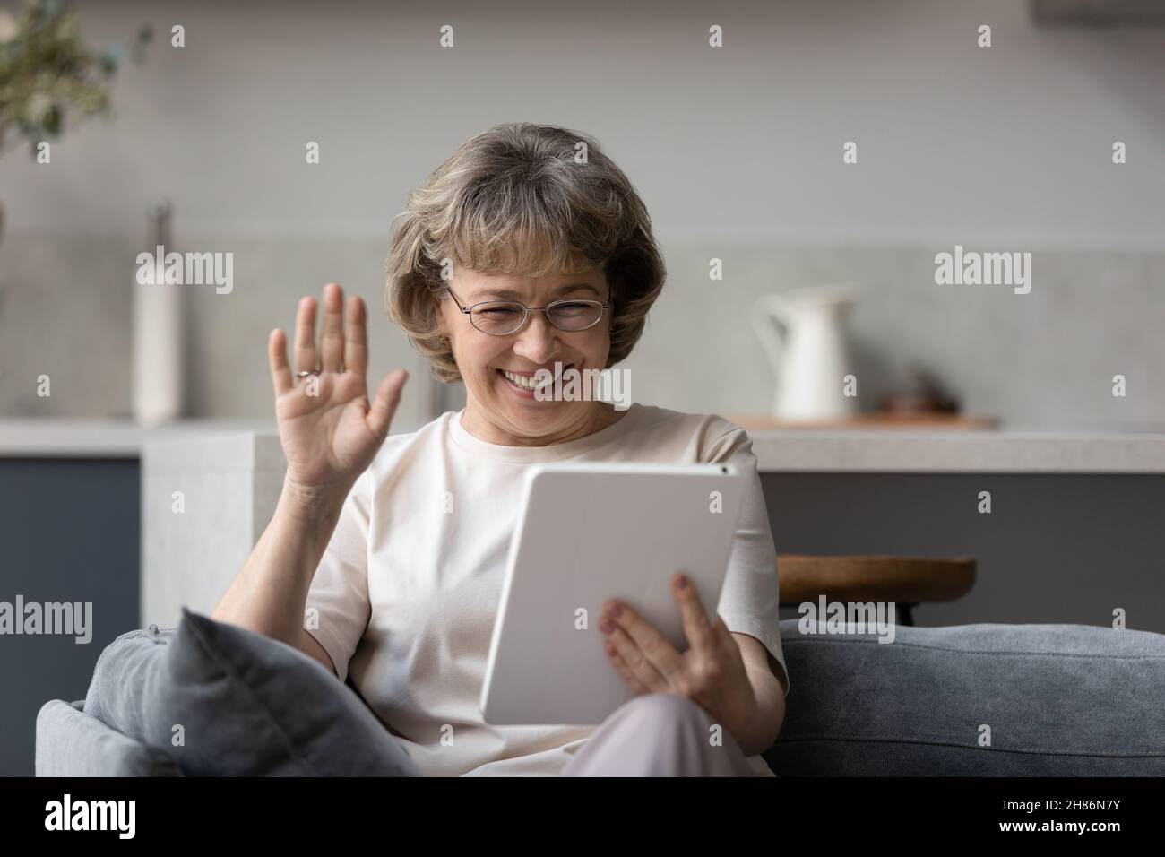 Glückliche reife 60s Frau winkende Hand hallo auf Tablet-Bildschirm Stockfoto