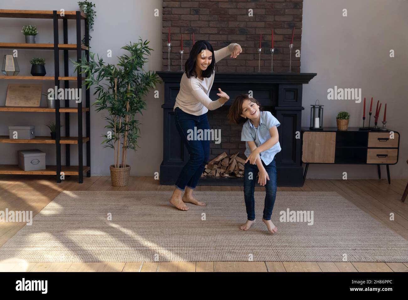 Aktiver asiatischer Babysitter und kleiner Junge, der im Wohnzimmer tanzt Stockfoto