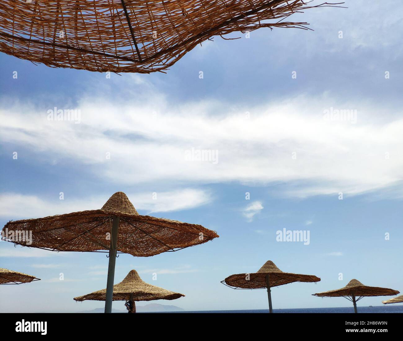 Sonnenschirme am Strand über blauem Himmel Hintergrund, Sommerurlaub Hintergrund Tapete Stockfoto
