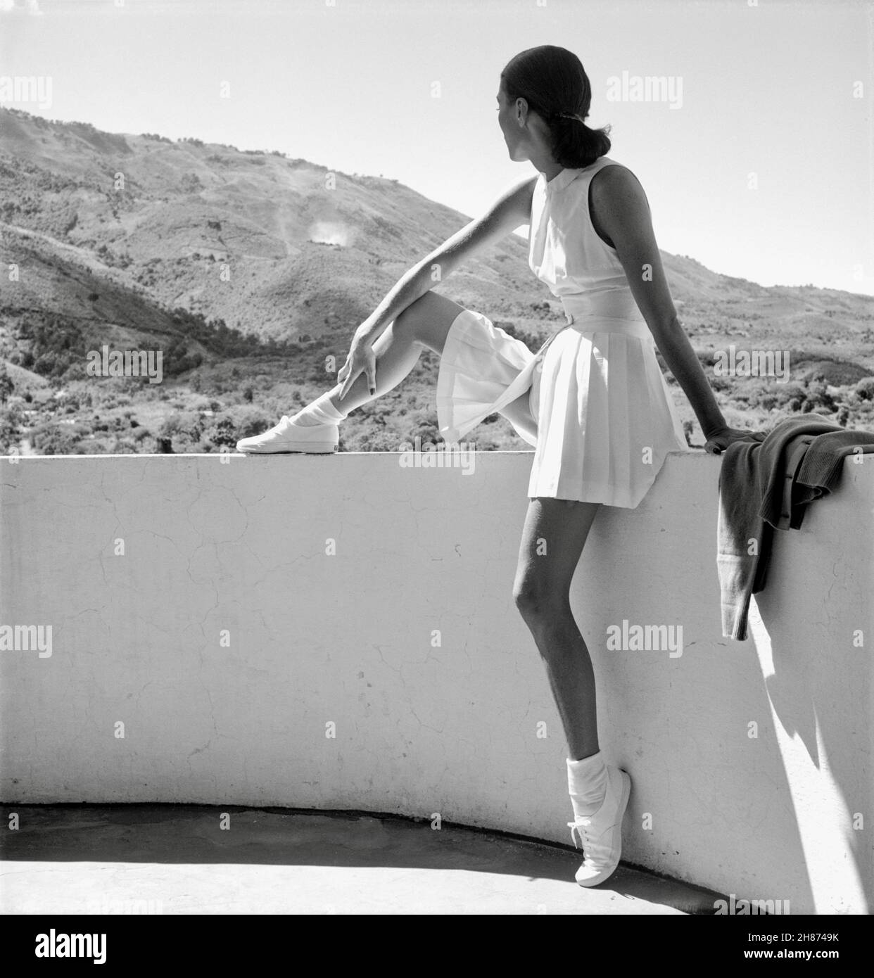 Toni Frisell - Frau im Tennis-Outfit sitzt und blickt in die bergige Landschaft - 1947 Stockfoto