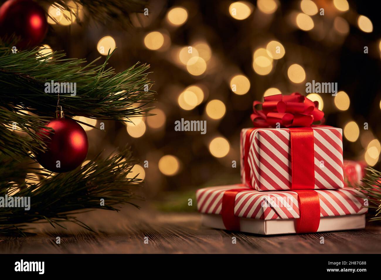 Weihnachts-Geschenkbox und Schmuckstücke auf einem Hintergrund von unfokussierten goldenen Lichtern. Stockfoto