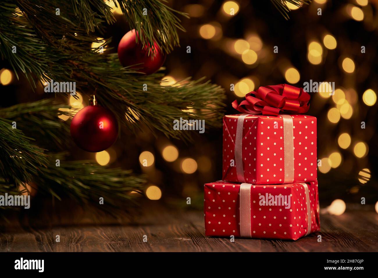 Rote Boxen mit Geschenken auf festlichem Weihnachtshintergrund. Stockfoto