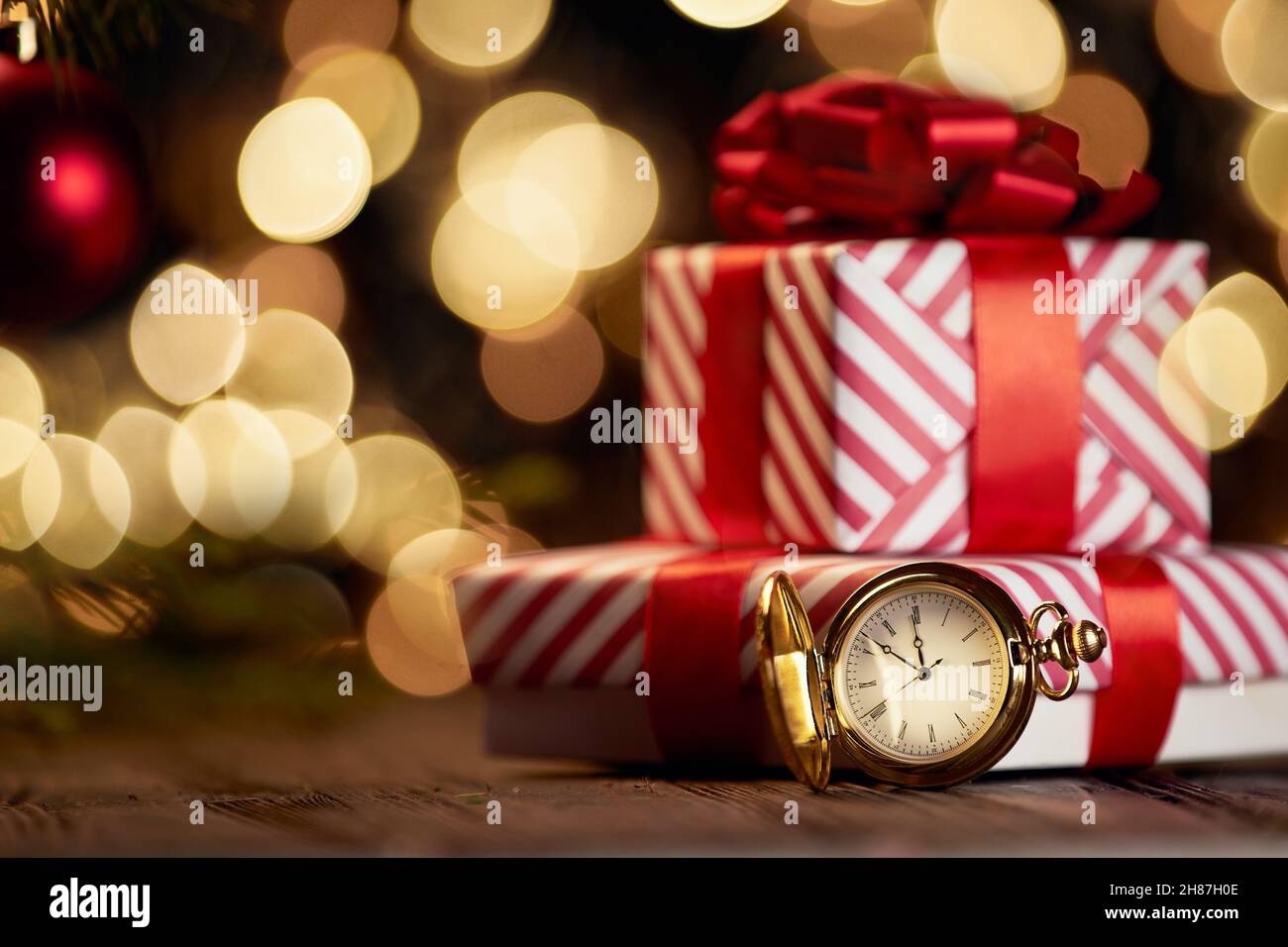 Uhren und Weihnachtskisten auf festlichem Hintergrund. Stockfoto