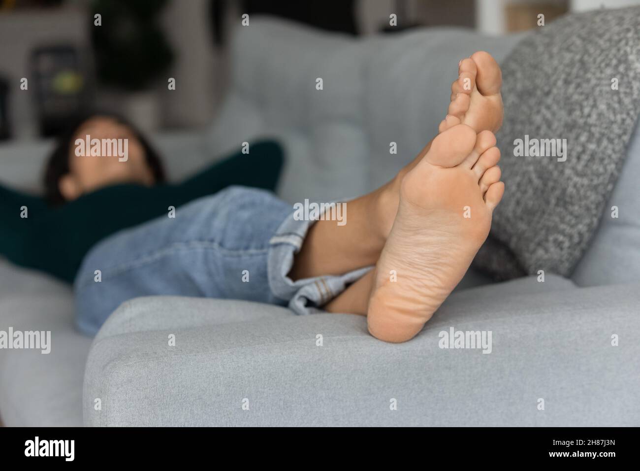 Konzentrieren Sie sich auf die Füße einer jungen Frau, die sich barfuß auf der Couch entspannt Stockfoto