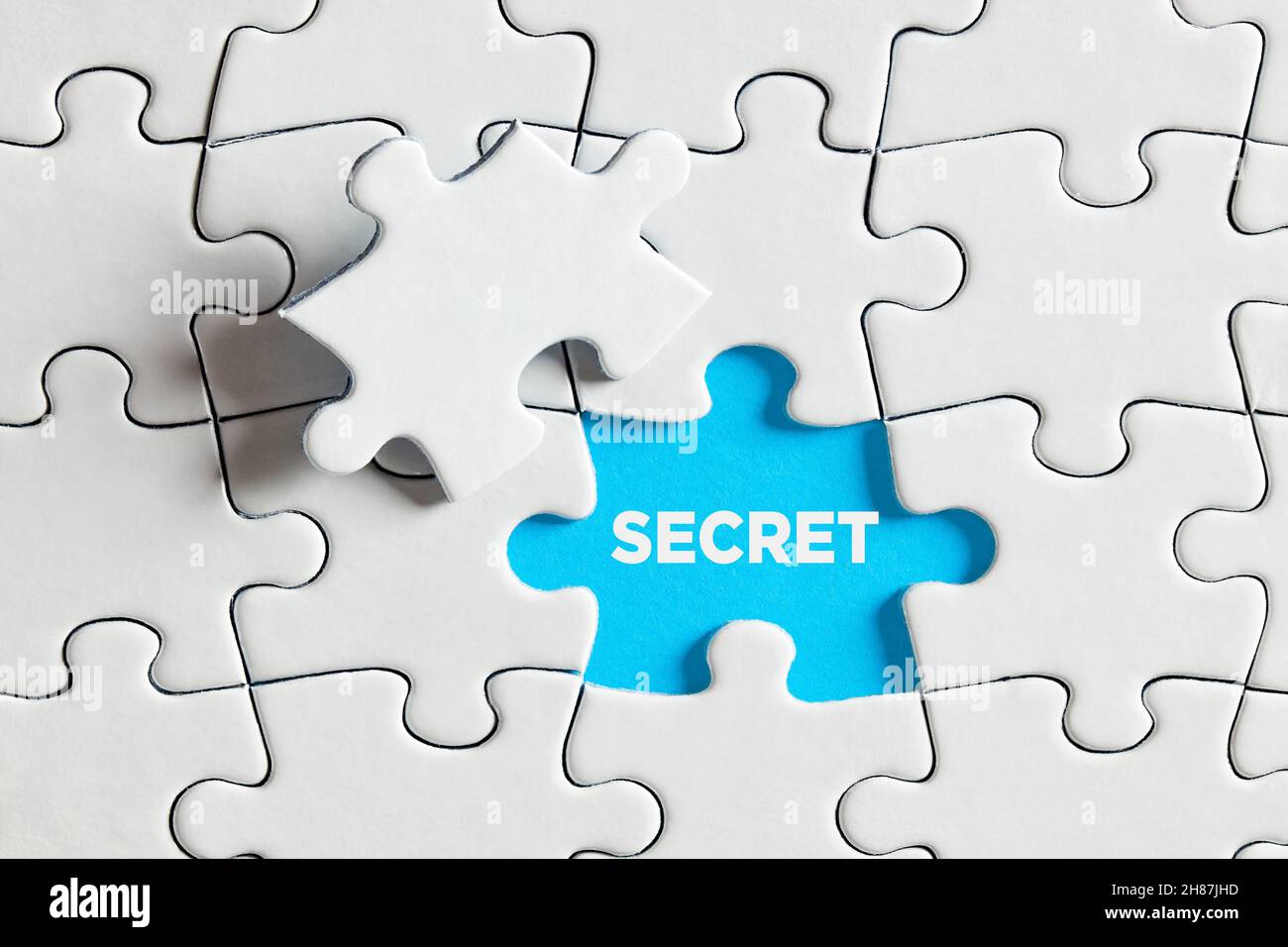 Um ein geheimes Konzept zu enthüllen oder zu entdecken. Das Wort Geheimnis auf blau fehlende Puzzleteil. Stockfoto