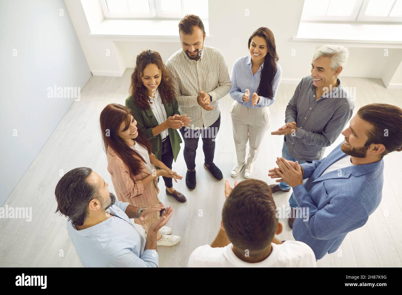 Menschen stehen im Kreis der Kontaktgruppe und applaudieren, ihre weibliche Führungskraft oder Kollegin zu unterstützen. Stockfoto