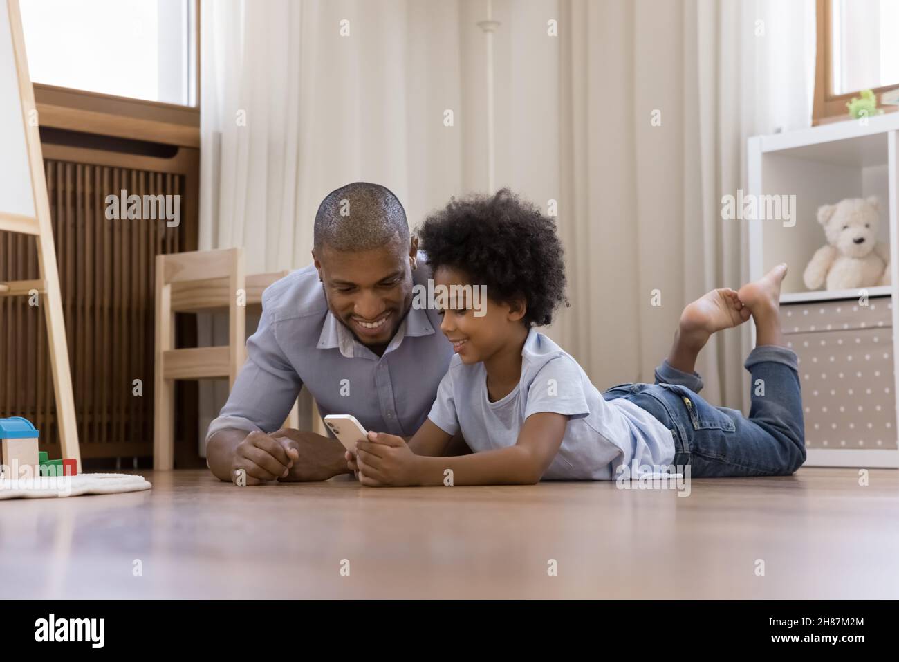 Happy Black Kind Junge und Vater ruhen auf warmen Boden Stockfoto