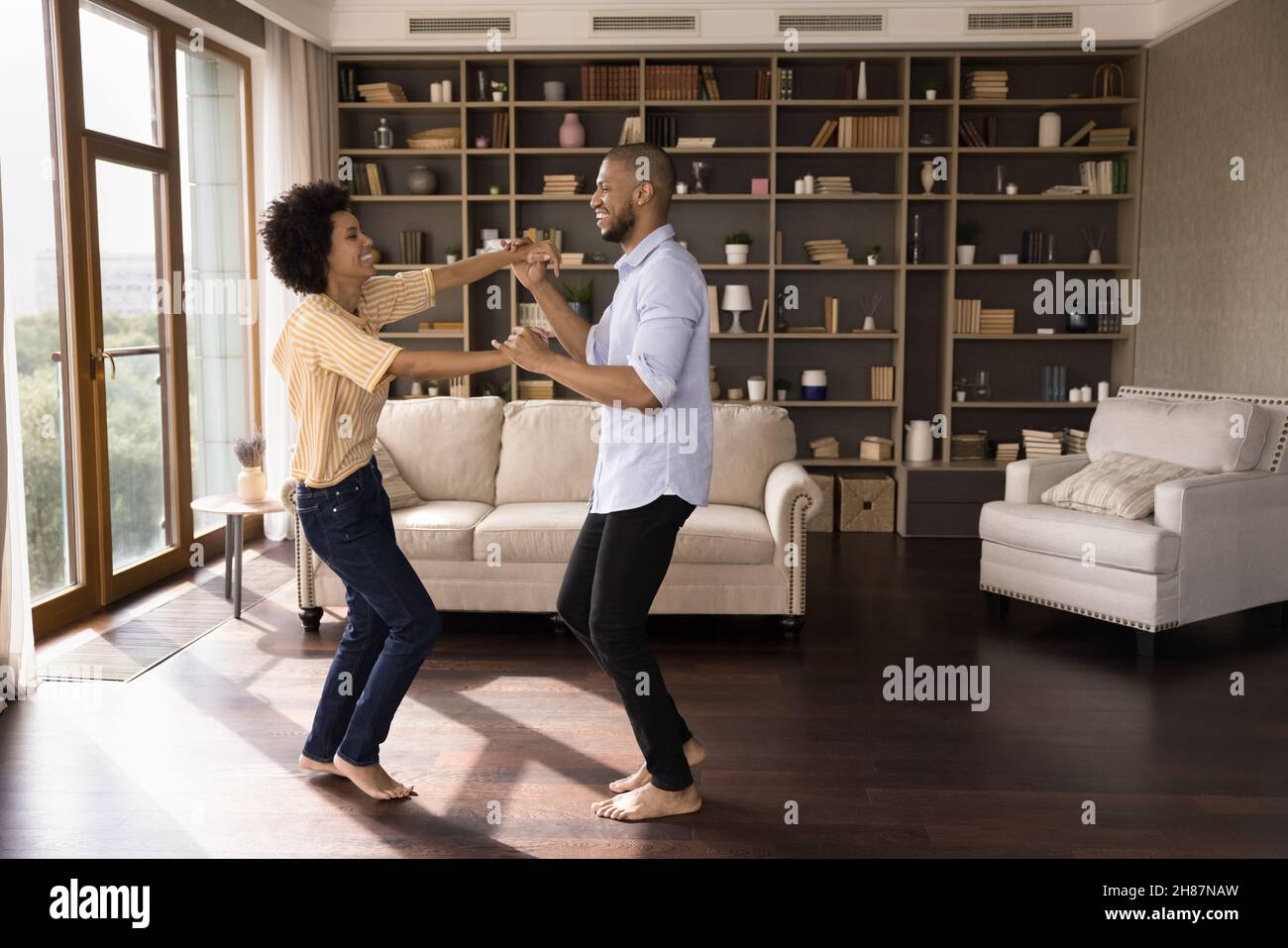 Fröhliches junges schwarzes Paar, das zu Musik in einem neuen Zuhause tanzt Stockfoto