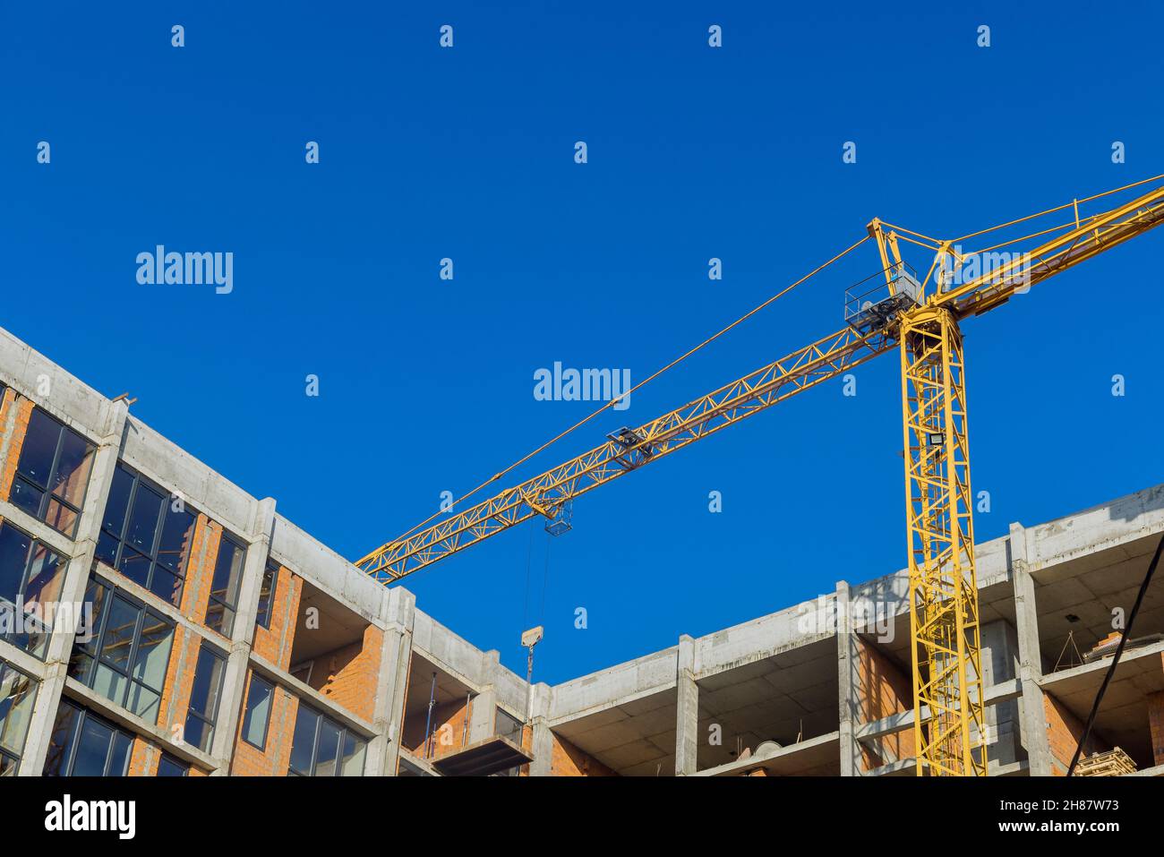 Luftaufnahme von oben auf der Baustelle neue mehrstöckige Gebäude Turmdrehkran mit unfertigen Hochhaus Stockfoto
