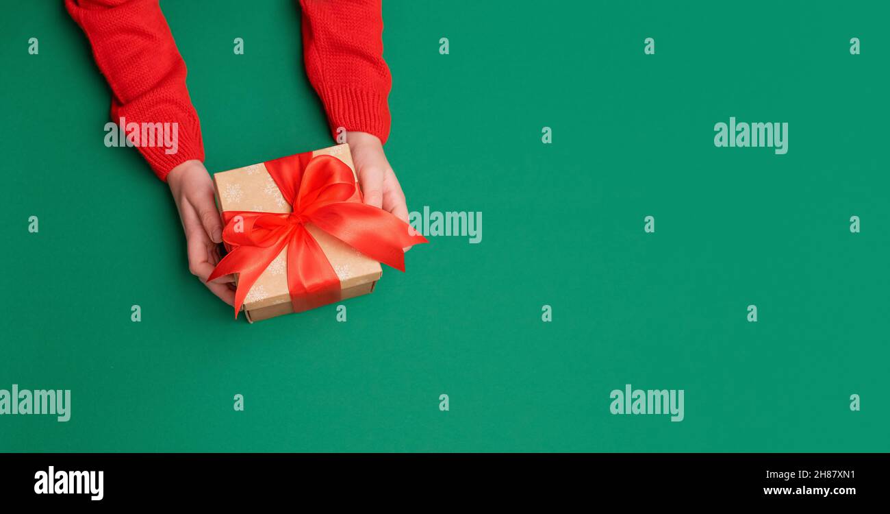 Grün blank Hintergrund, Hände in Silvester Pullover halten Geschenk mit Band Stockfoto