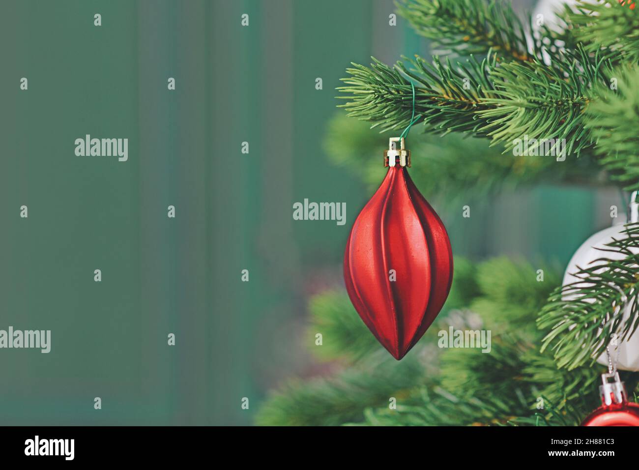 Elegante rote weihnachtskugel auf Baum vor grünem Hintergrund mit Kopierraum Stockfoto