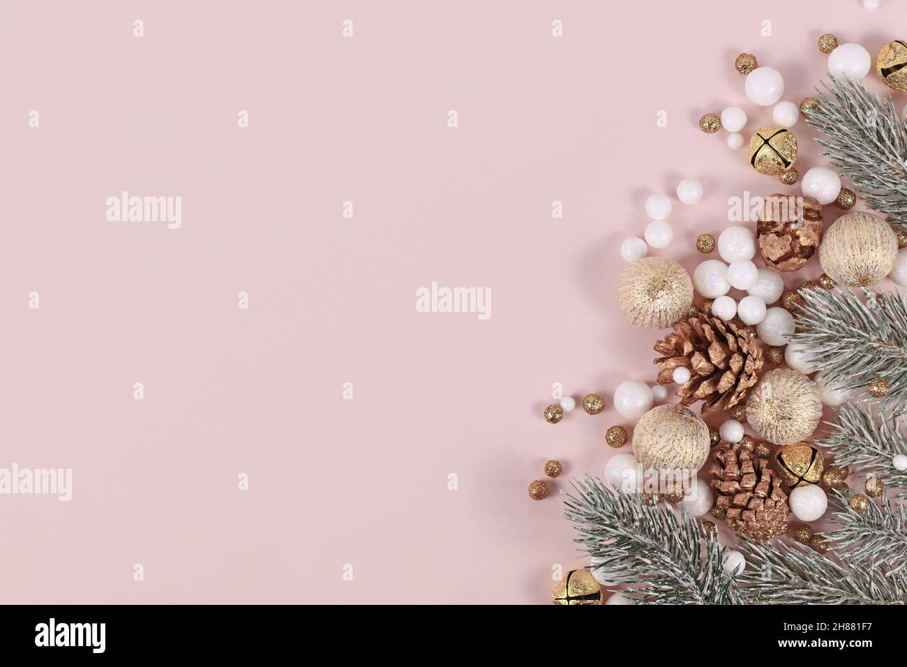 Weihnachtsbanner mit für Äste, Zapfen, goldene Baumkugeln und Schneebällen auf rosa Hintergrund mit Kopierraum Stockfoto