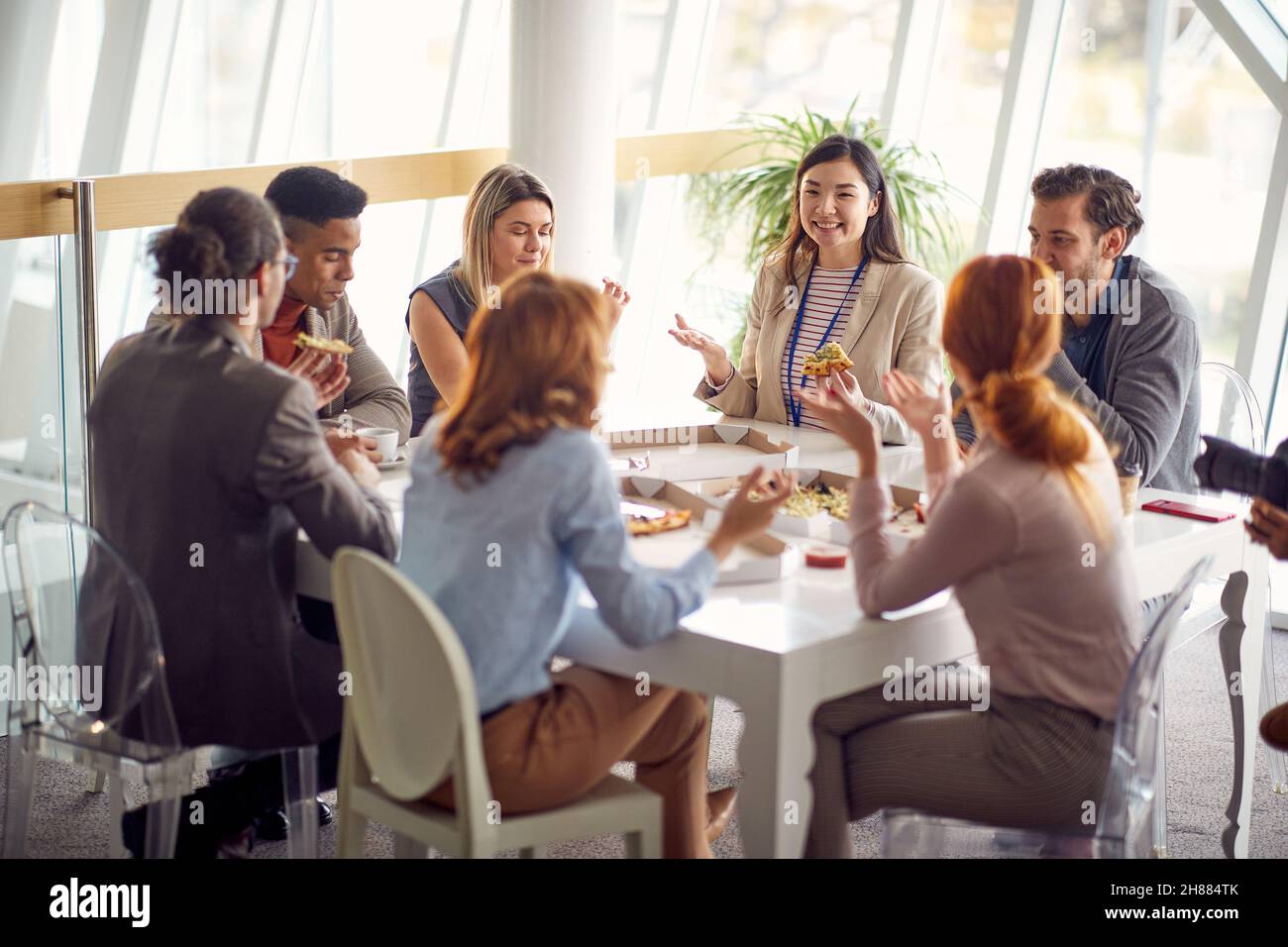 Eine Gruppe junger Geschäftsleute genießt gemeinsam eine Mittagspause bei der Arbeit in einer freundlichen Atmosphäre. Unternehmen, Mitarbeiter, Unternehmen Stockfoto