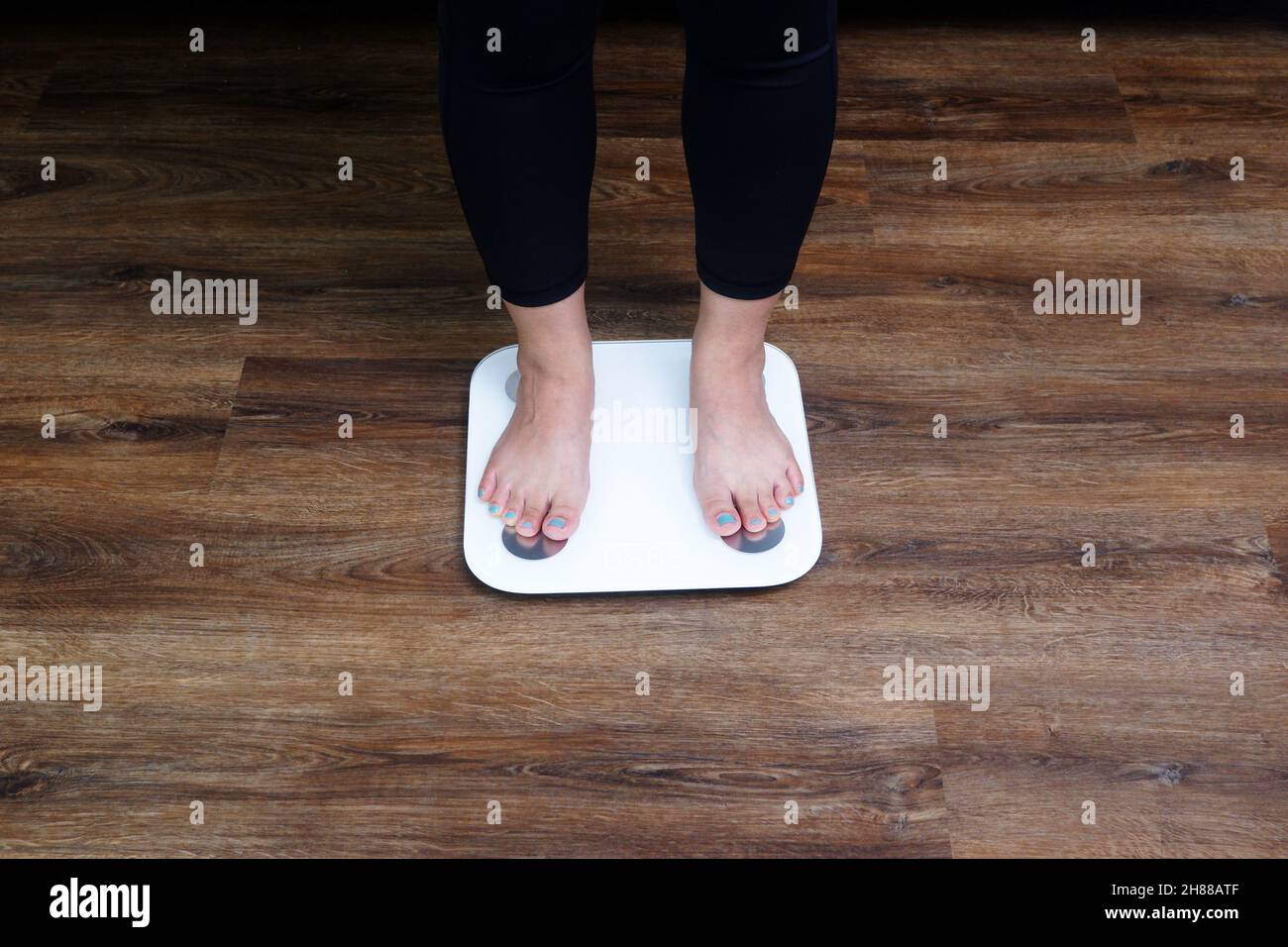 Nahaufnahme der weiblichen Füße, die auf die Körpergewichtskala treten. Gewichtskontrolle, Gewichtsverlust Konzept. Stockfoto