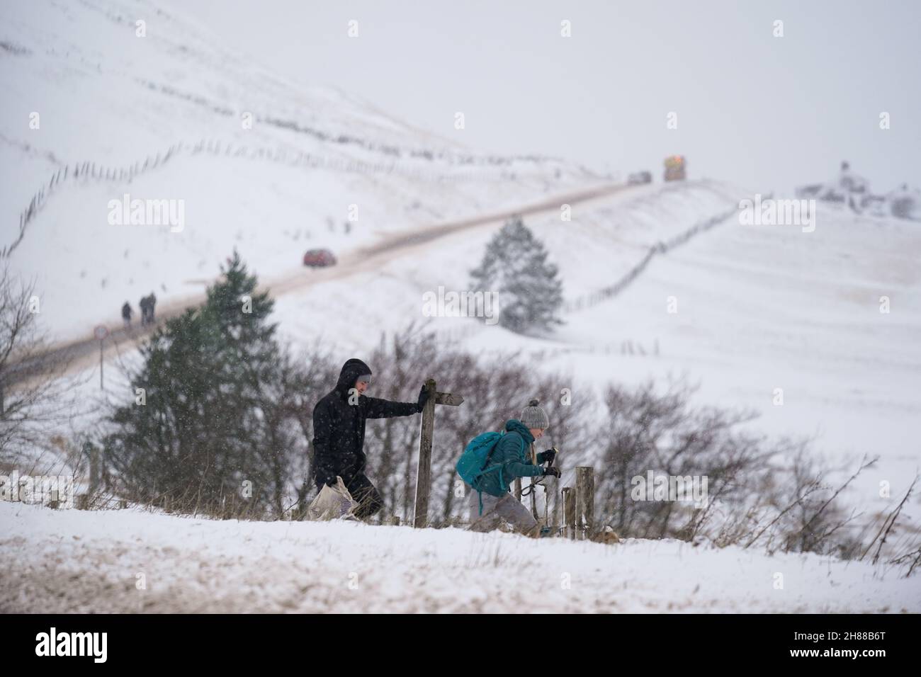 Wanderer überqueren das schneebedeckte Feld der A53 in der Nähe von Buxton in Derbyshire, inmitten eisiger Bedingungen nach dem Sturm Arwen. Bilddatum: Sonntag, 28. November 2021. Stockfoto