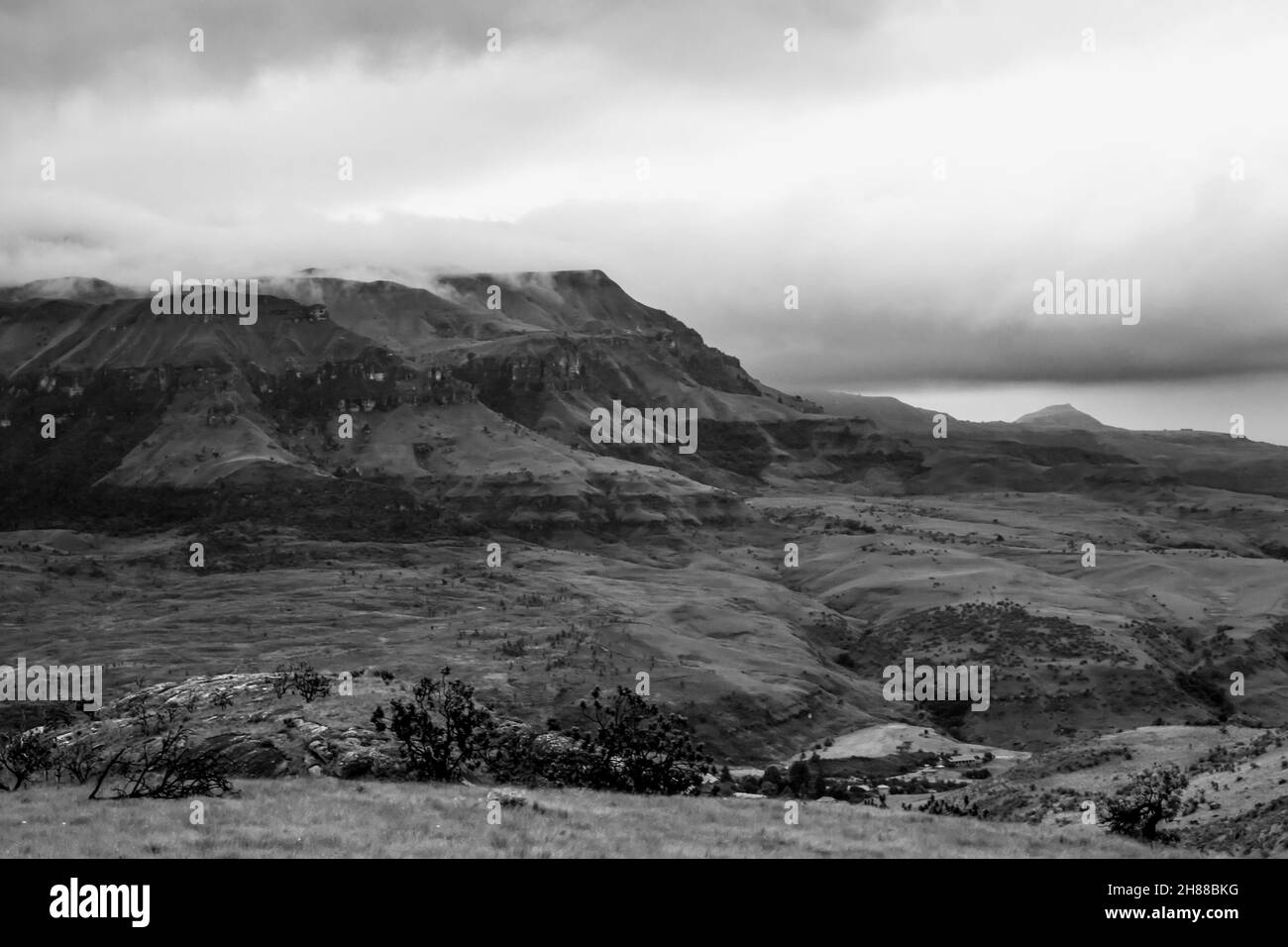 Ein Sturm, der sich sammelt, mit den tief liegenden Wolken, die die auf der Spitze eines entfernten Berges, in den Drakensberg Bergen von Südafrika, in Schwarz und bedeckt Stockfoto